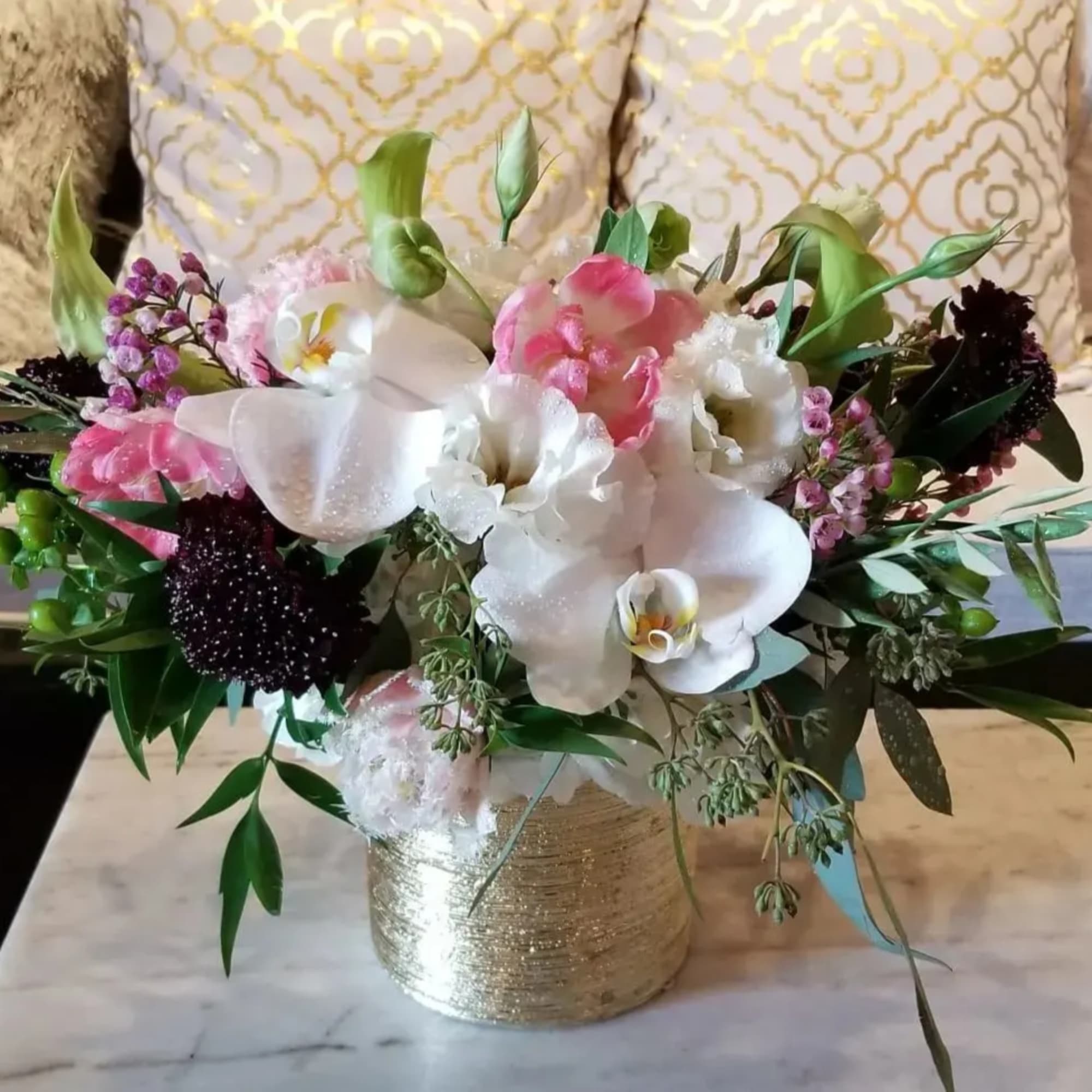 Pink and white floral arrangement in a gold vase