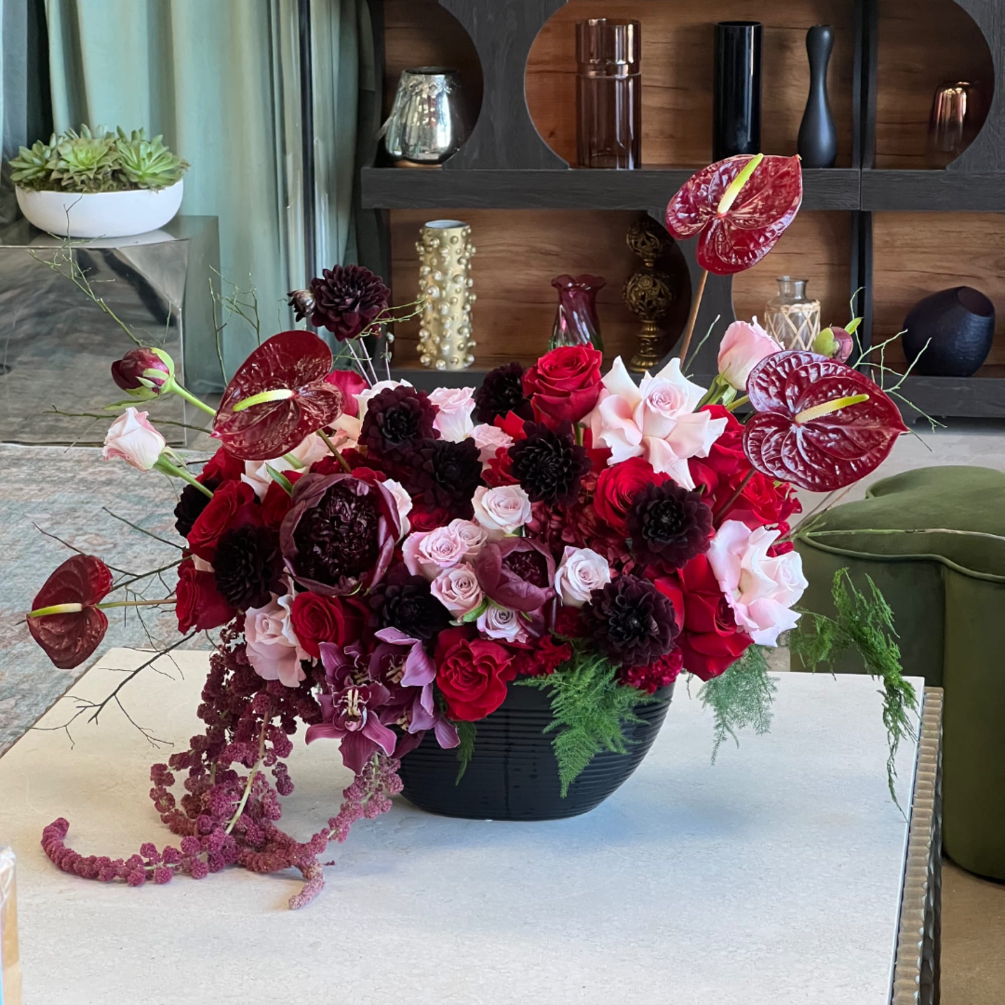 Red and pink floral arrangement in a black bowl vase