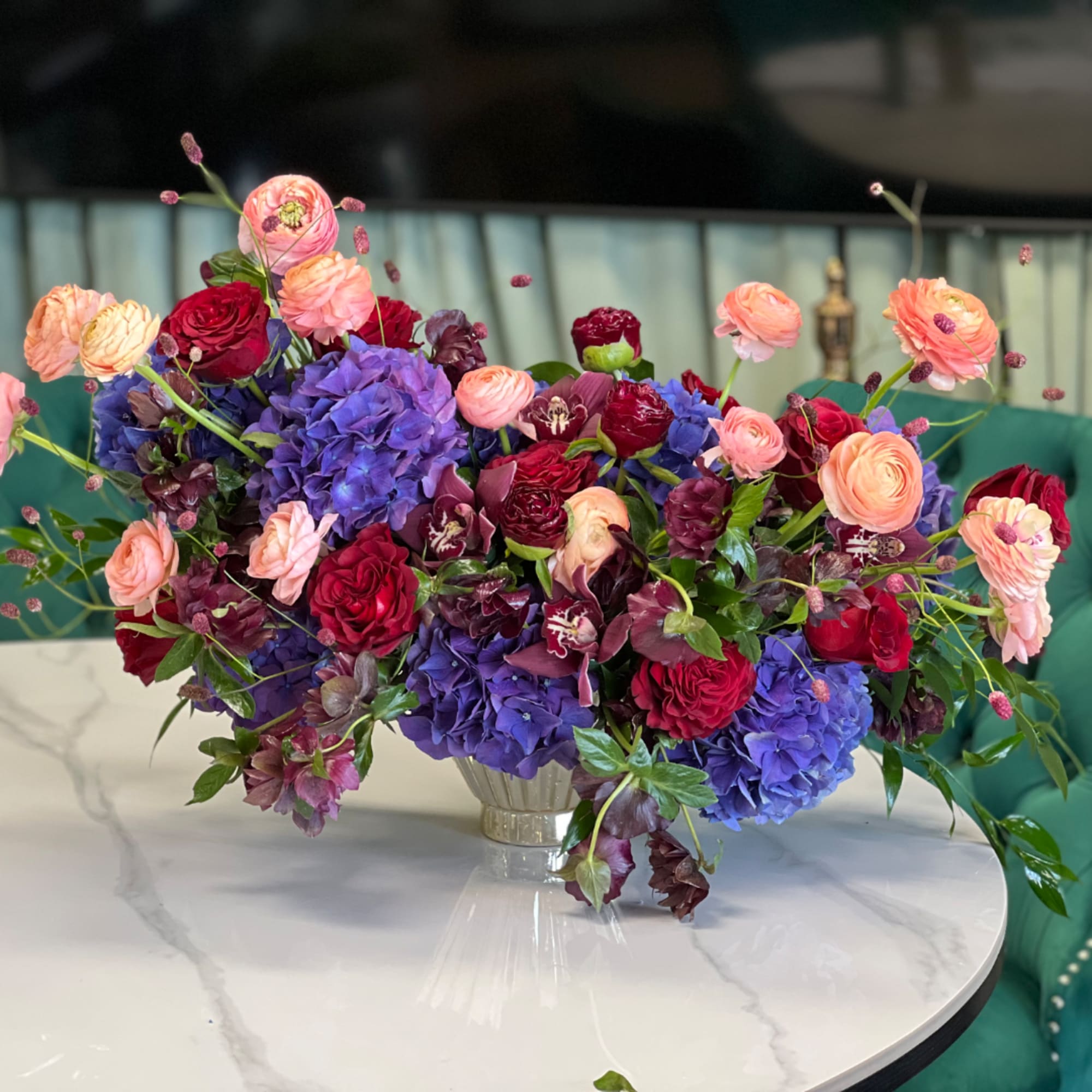 Colorful bouquet of roses, ranunculus, and hydrangeas in a glass vase