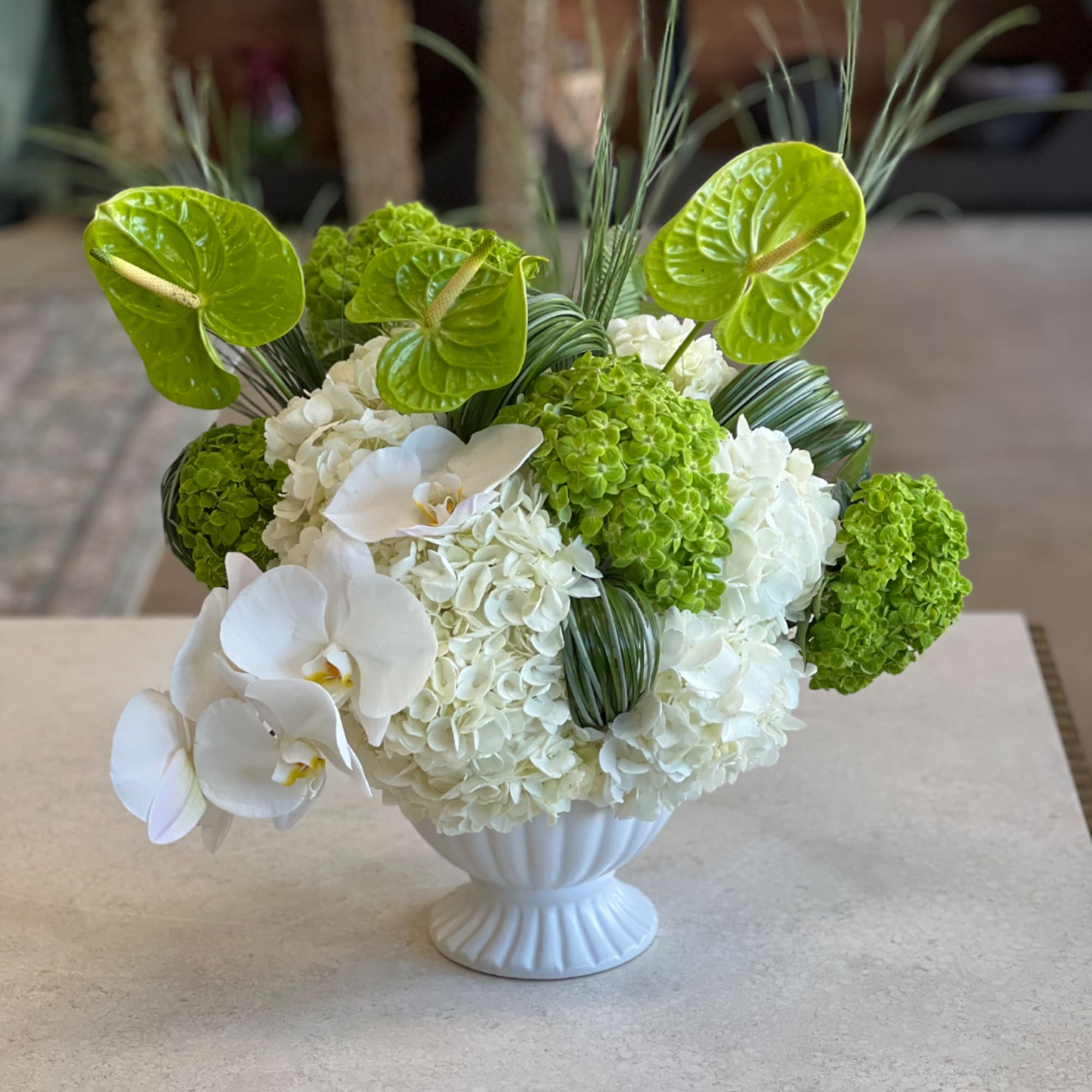 White orchids and green hydrangeas in a white vase
