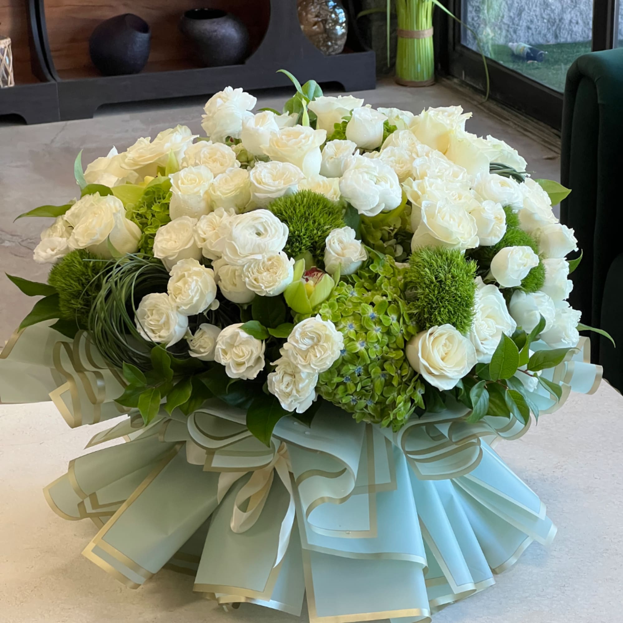 Large white rose bouquet with green accents and a pale ribbon wrap