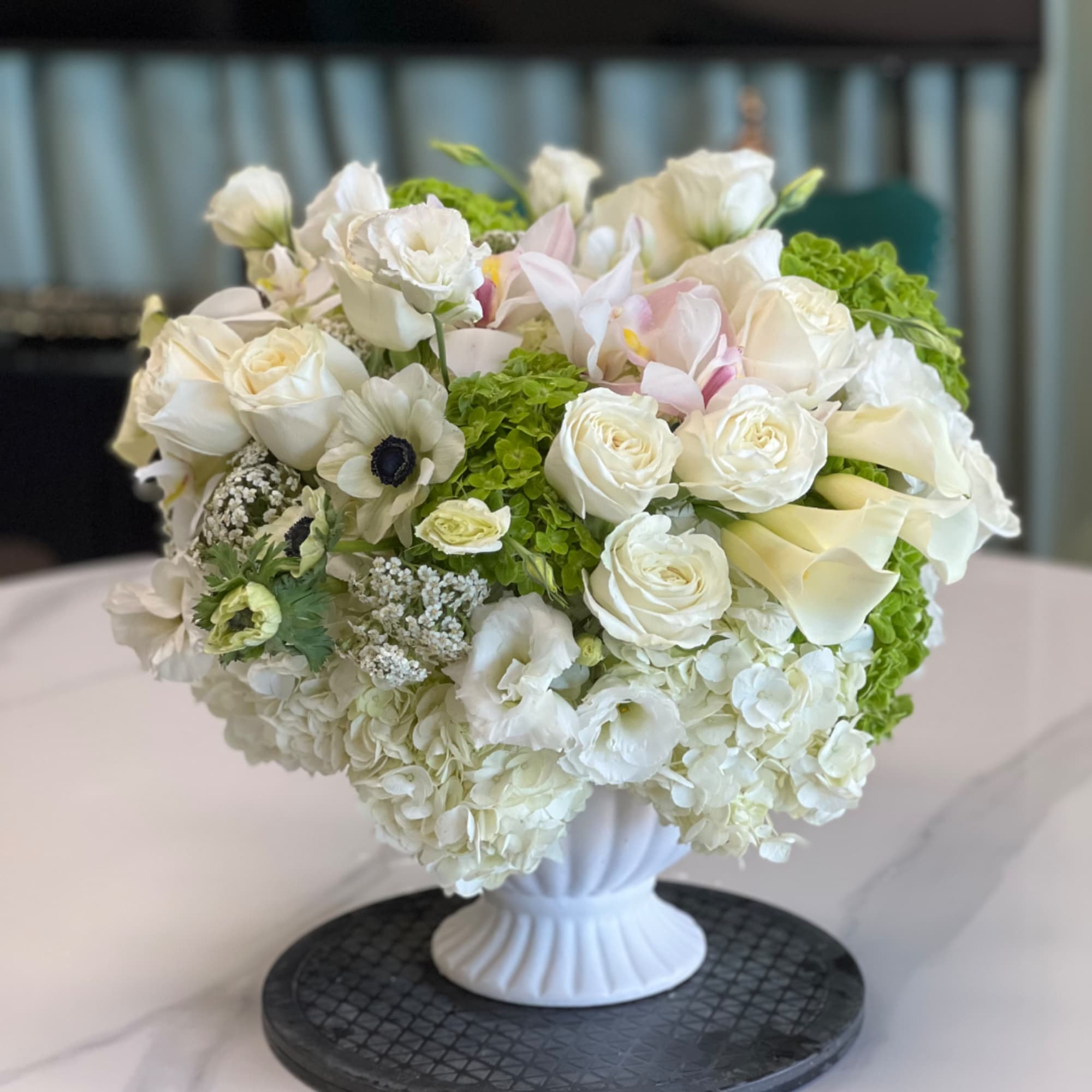 White floral arrangement in a white pedestal vase with green accents, photo 2 of 2