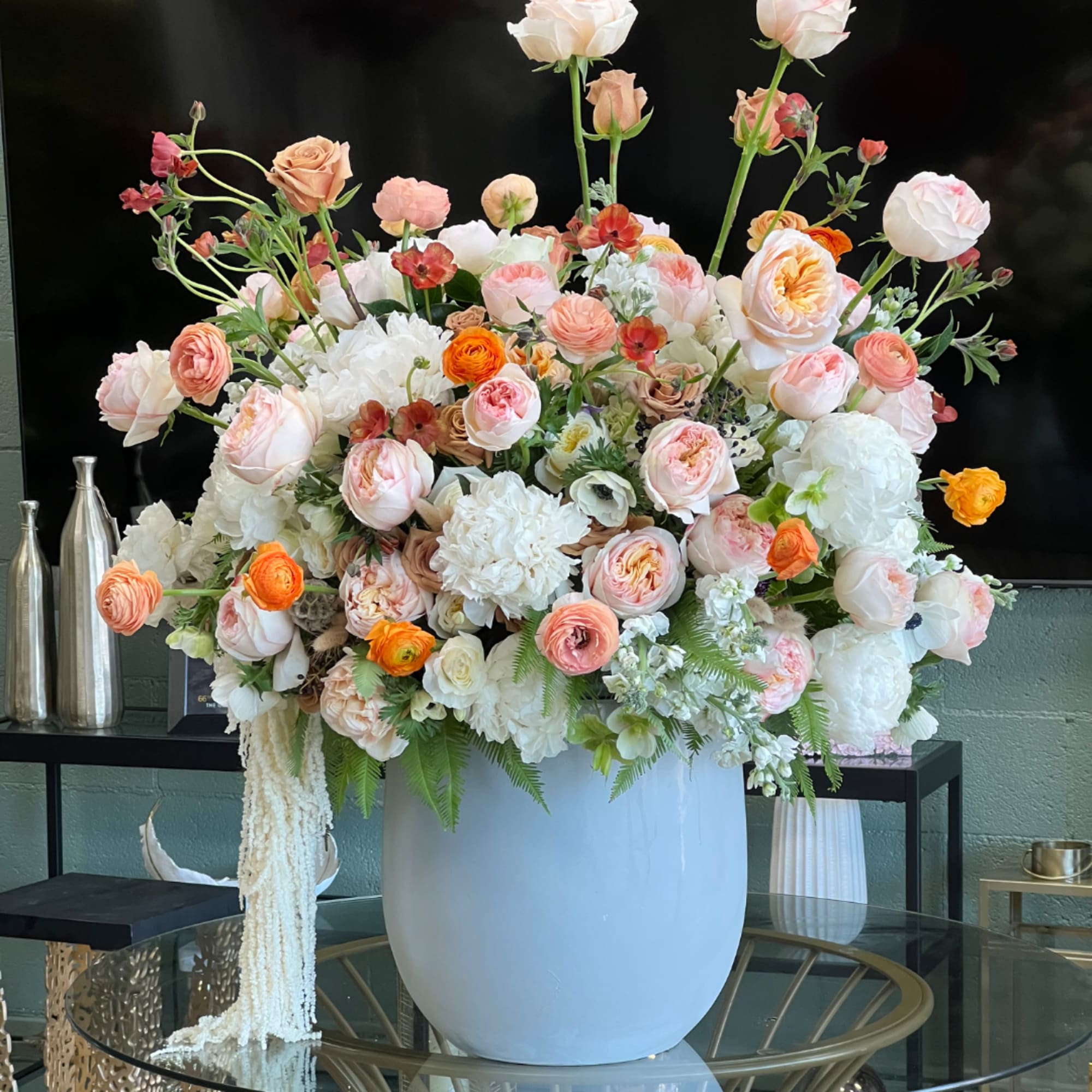 Large pastel floral arrangement in a white vase with roses and ranunculus