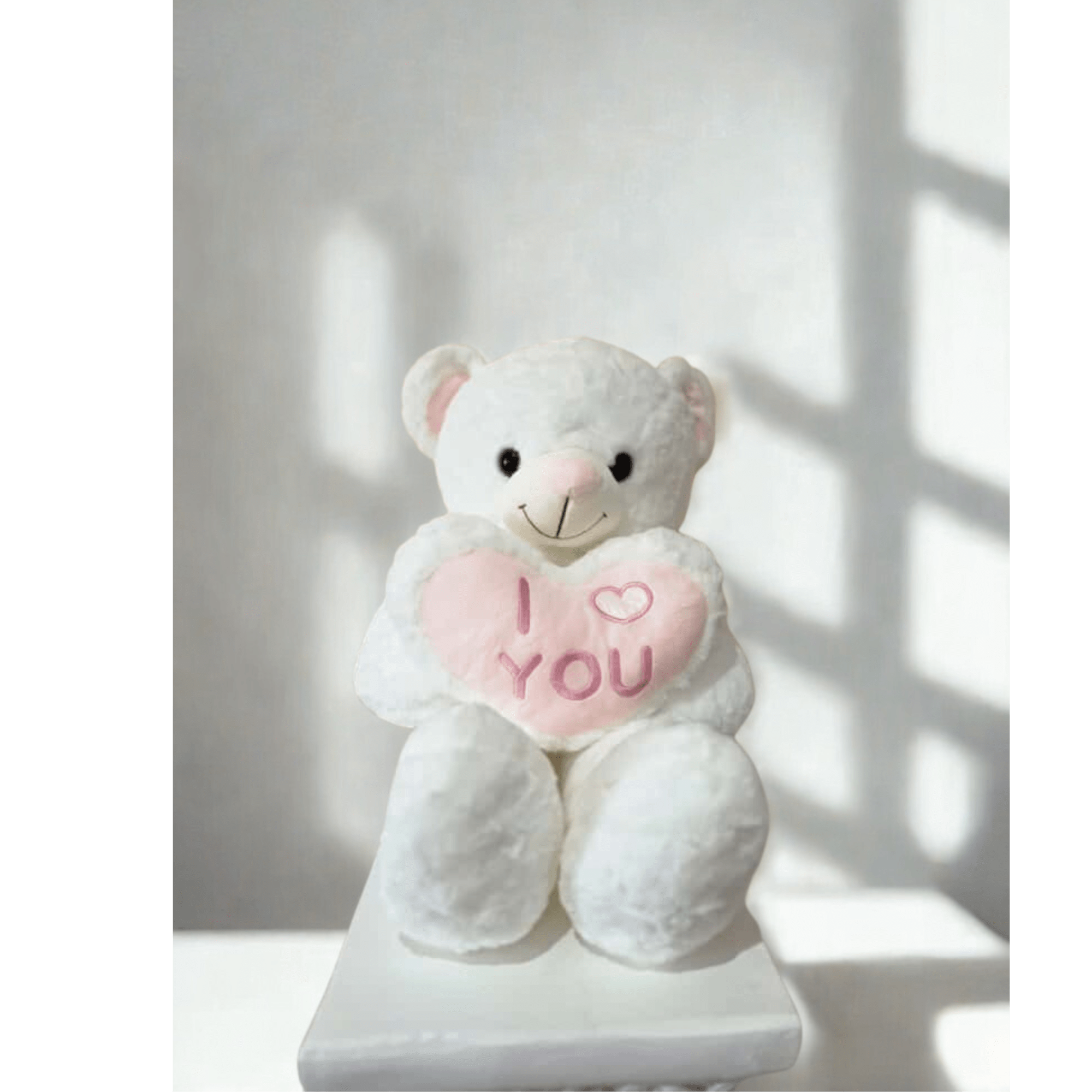 White teddy bear holding a pink heart that says I love you