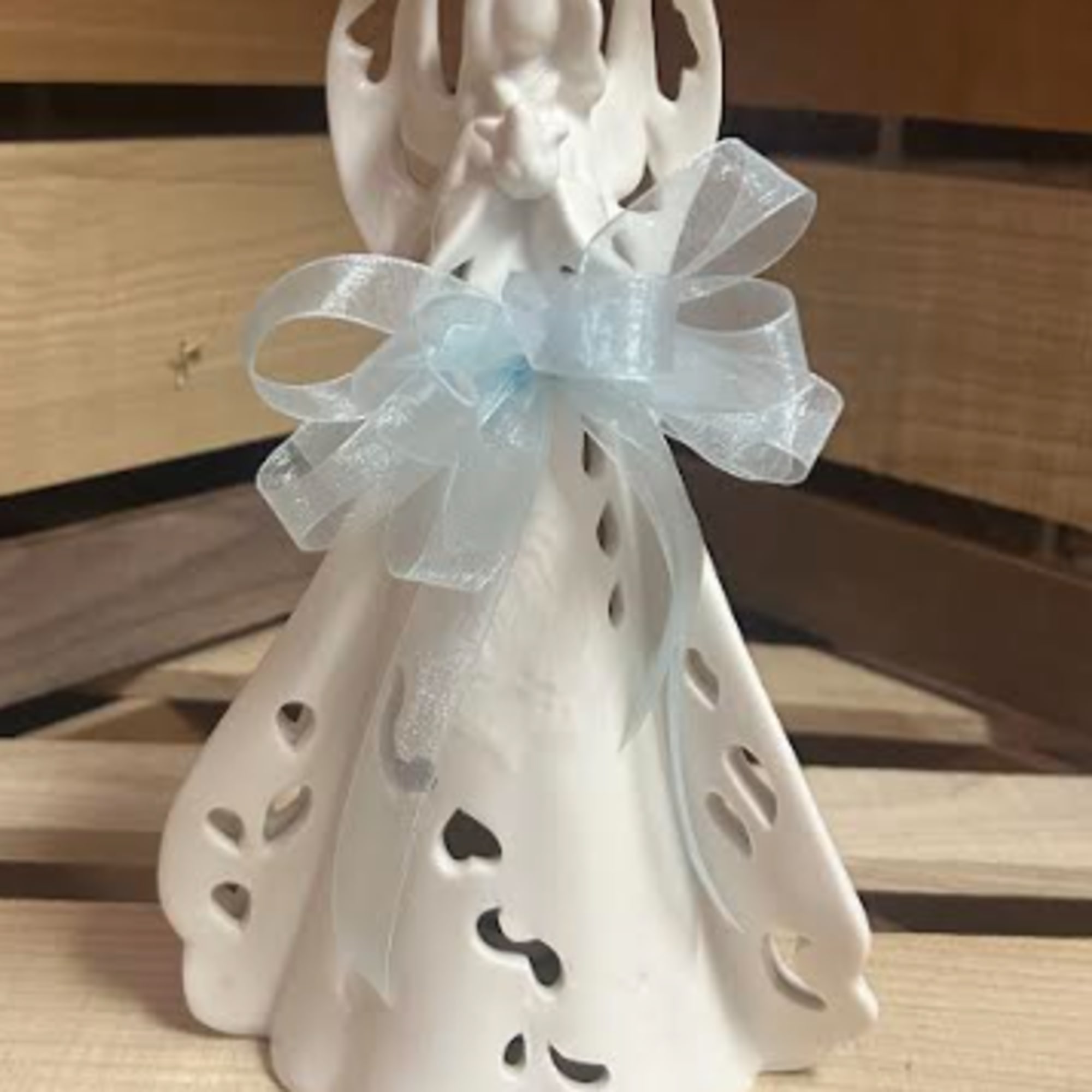 White ceramic angel figurine with a pale blue ribbon bow