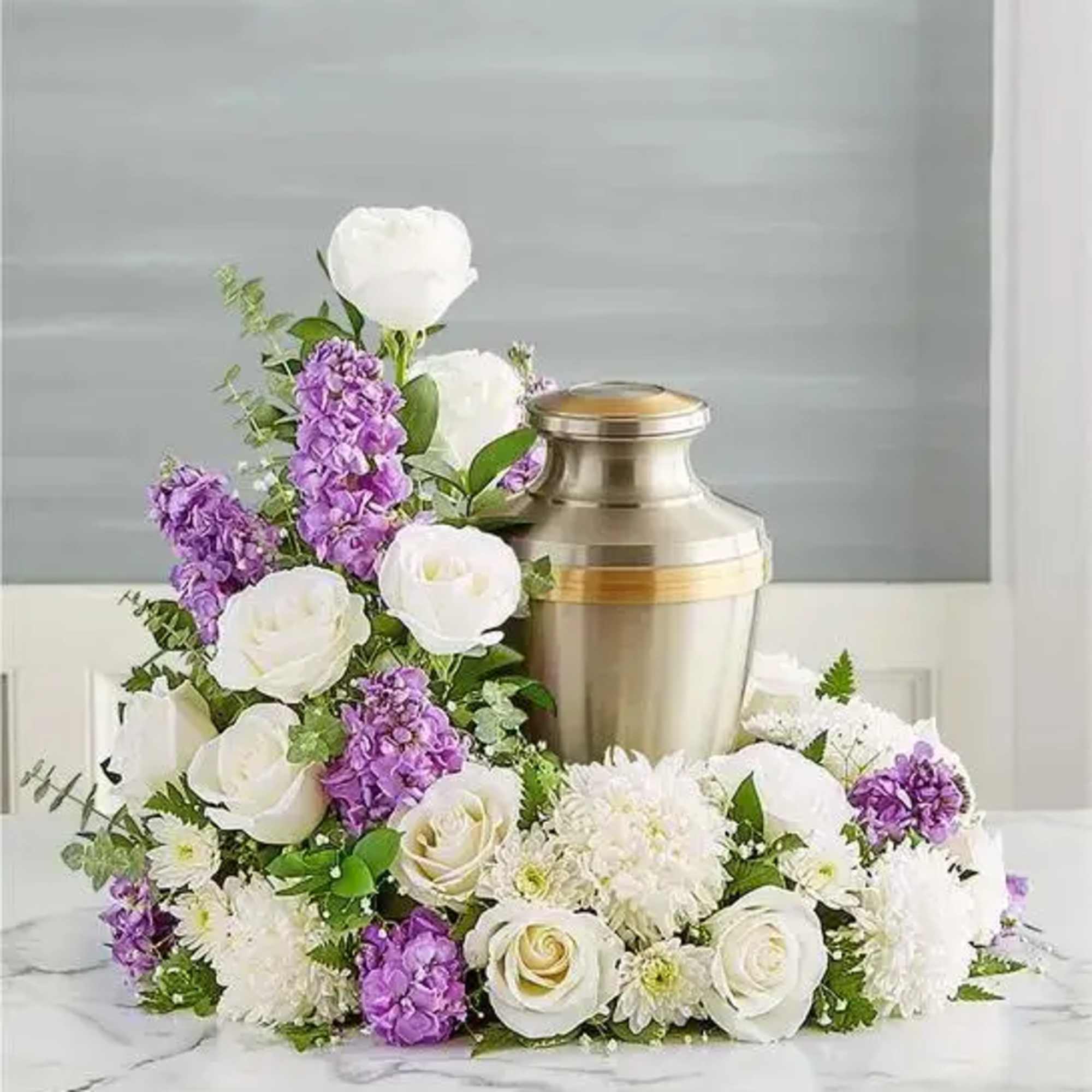 White and purple floral arrangement around a silver urn