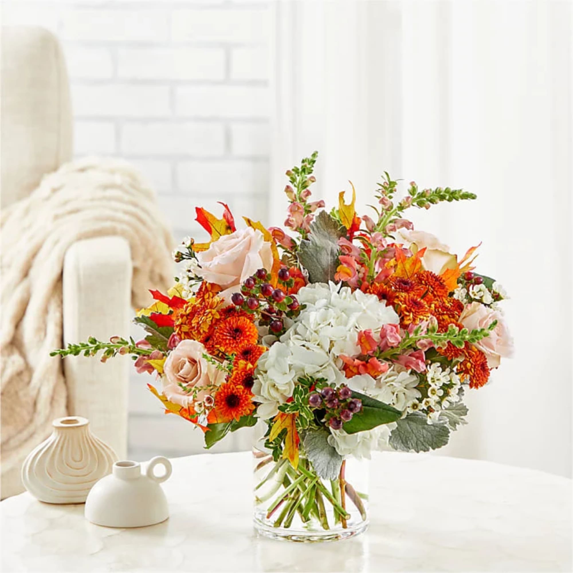 Autumn bouquet of orange and white flowers in a clear glass vase