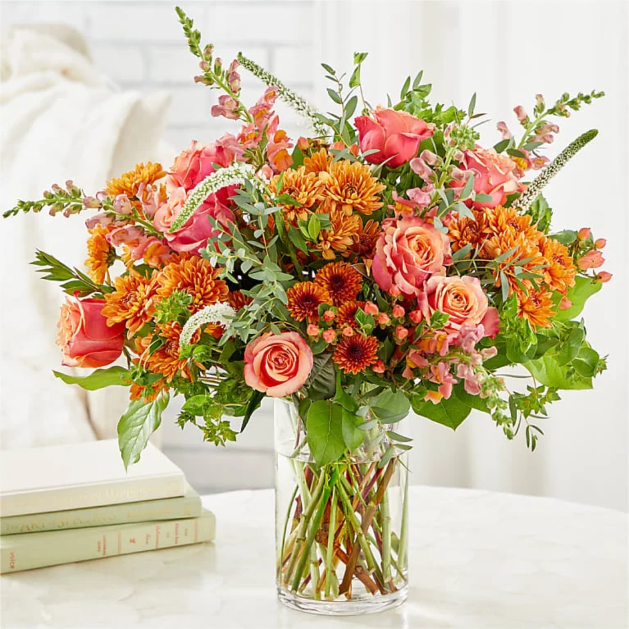 Pink roses and orange mums in a clear glass vase