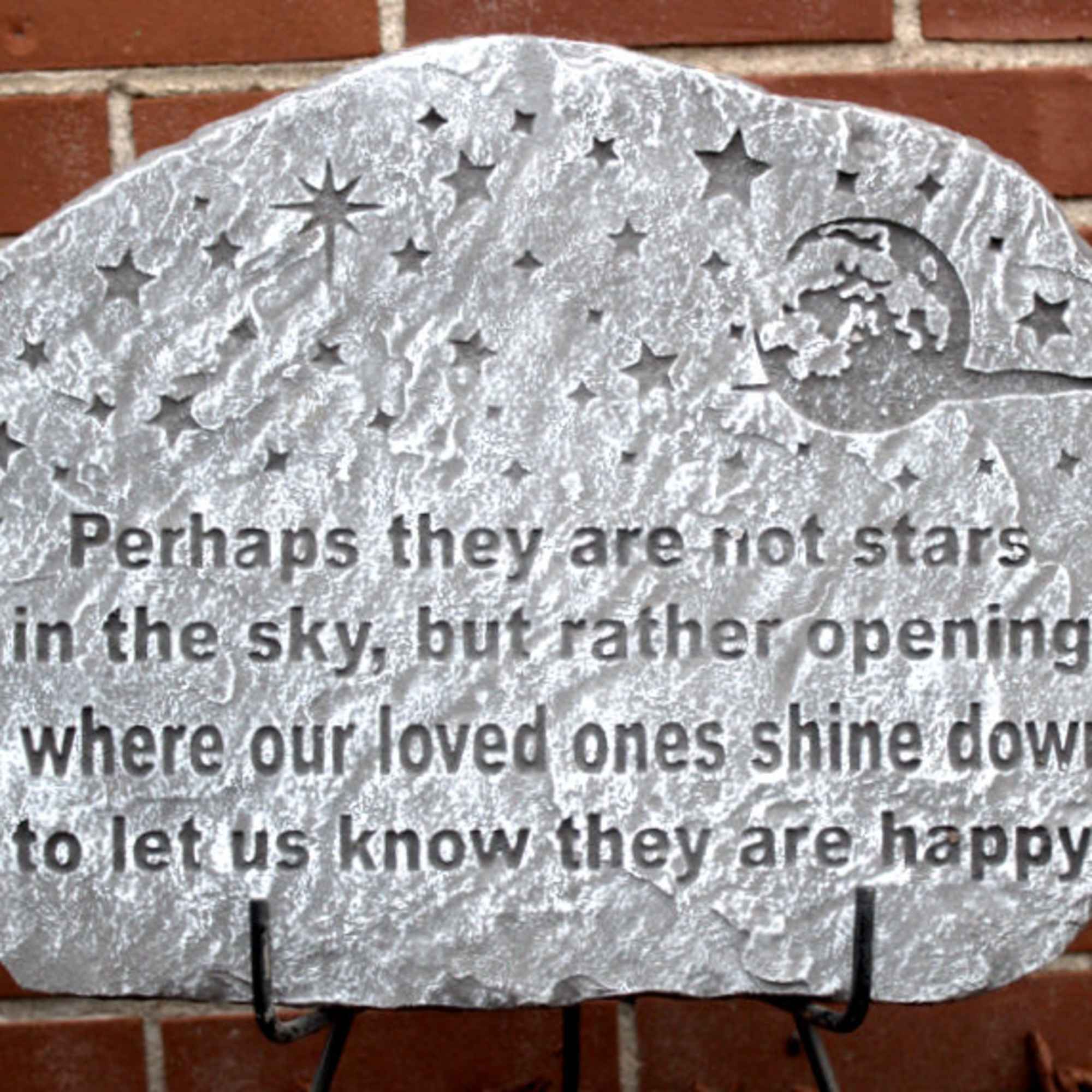 Decorative memorial stone plaque with a starry quote on a brick wall