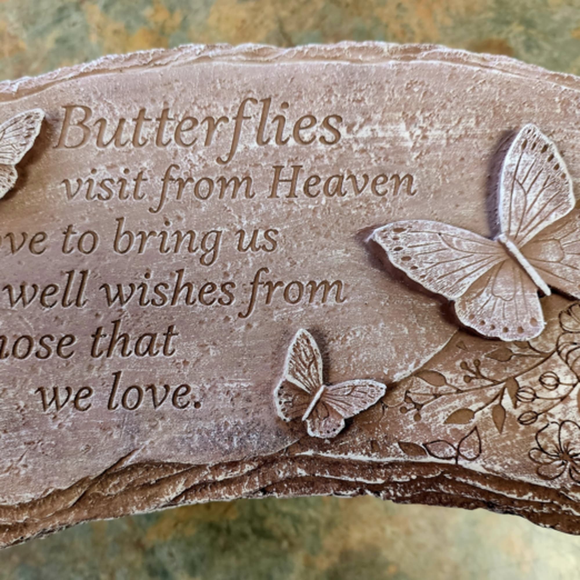 Stone plaque with raised butterflies and a memorial quote engraved on the surface