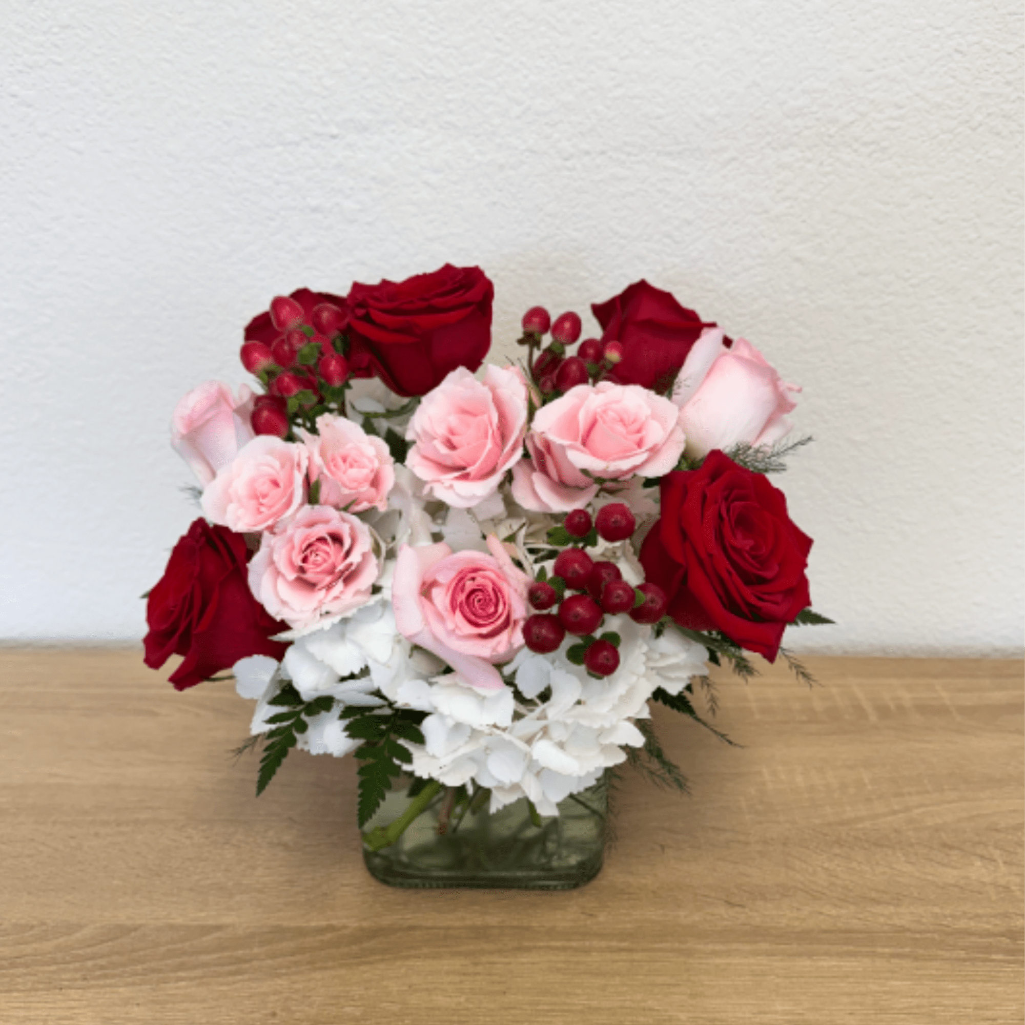 Cube arrangement with white hydrangea, red roses, pink roses, pink spray roses