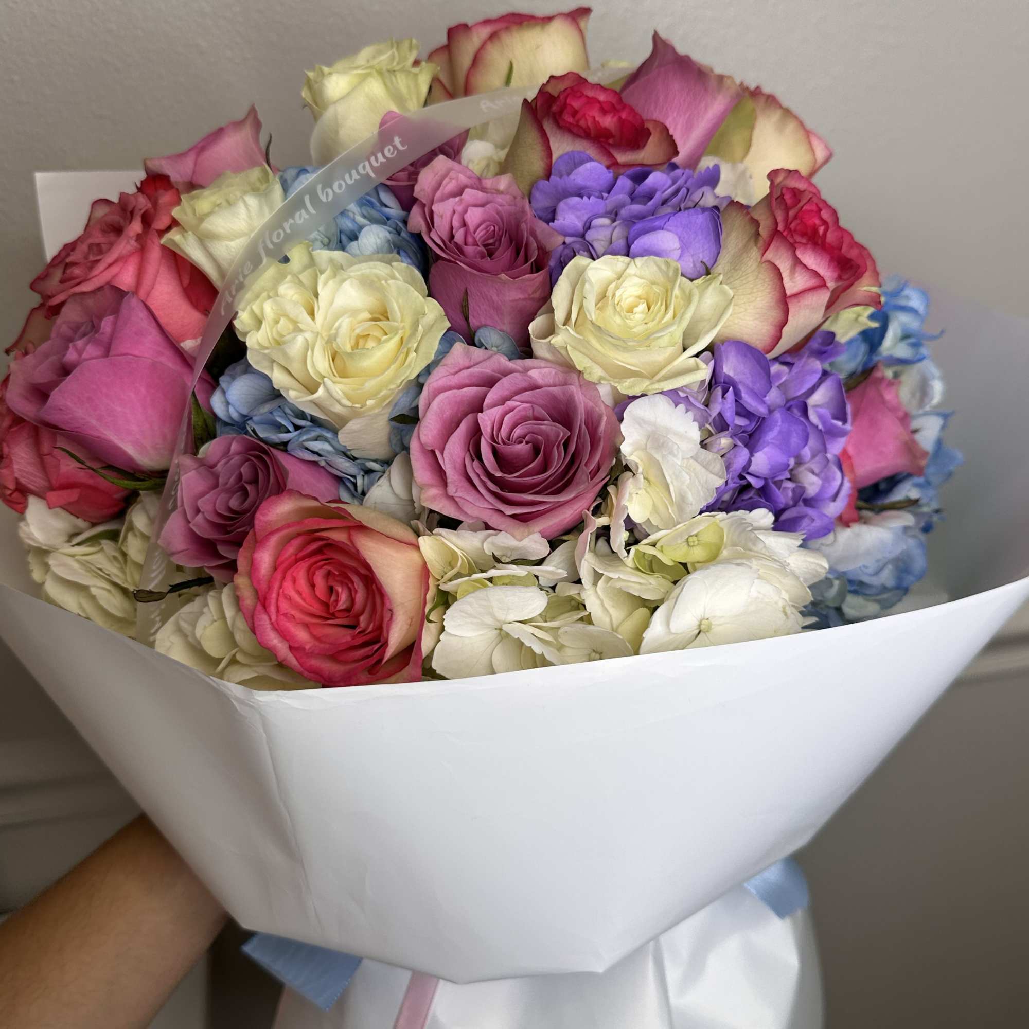 Bouquet of multicolored roses wrapped in white paper