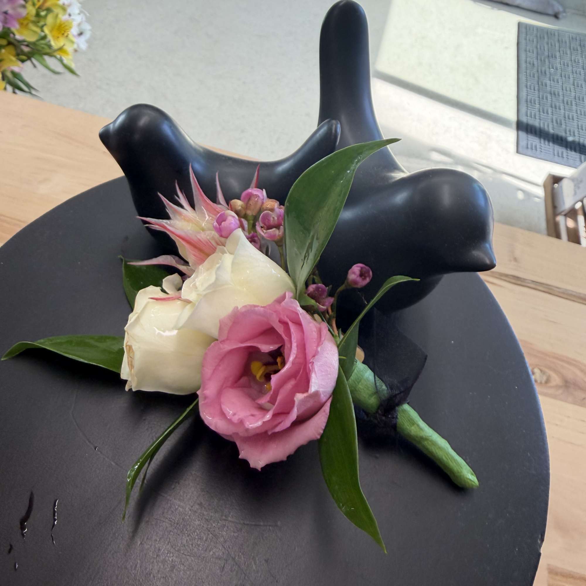 Small boutonniere with pink and white flowers on a black display stand
