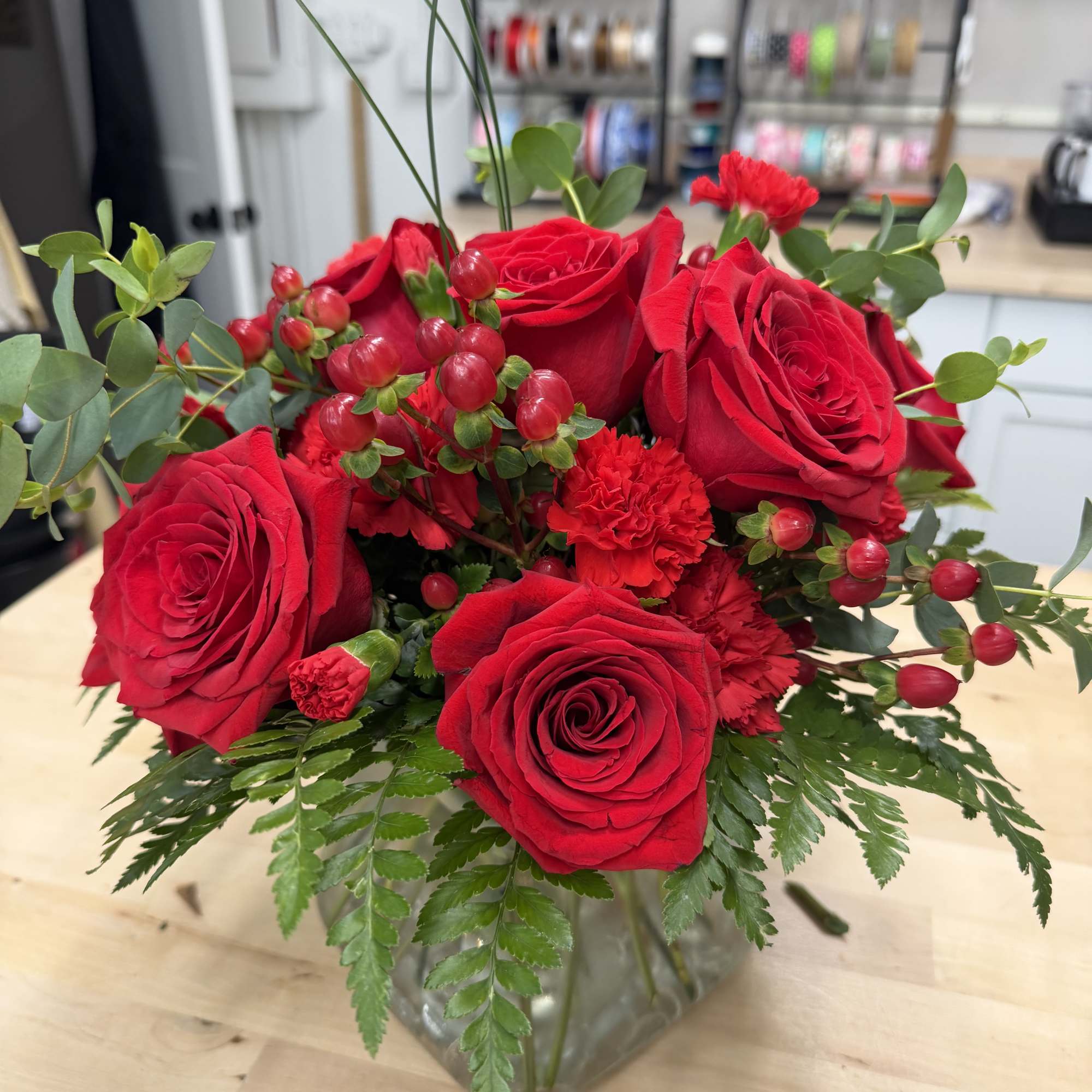 Red roses and carnations arranged in a clear glass vase