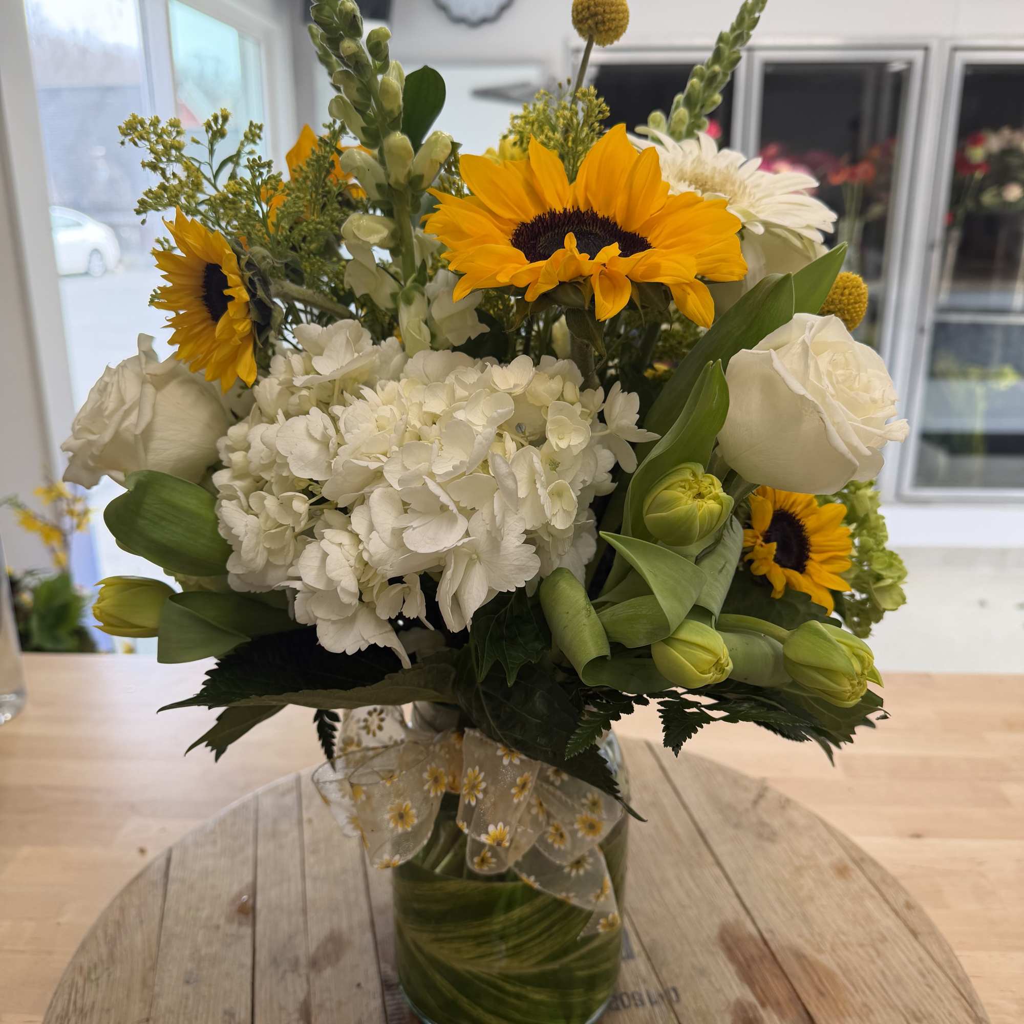 Bouquet of sunflowers, white hydrangea, and white roses in a glass vase