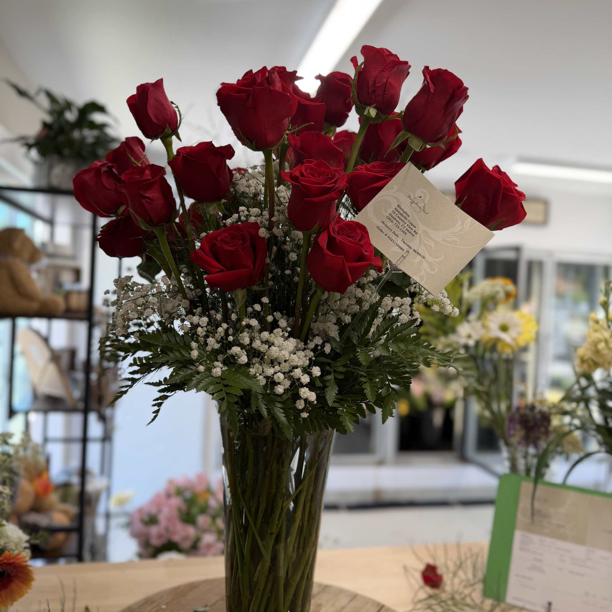 Tall vase arrangement of red roses with white baby's breath