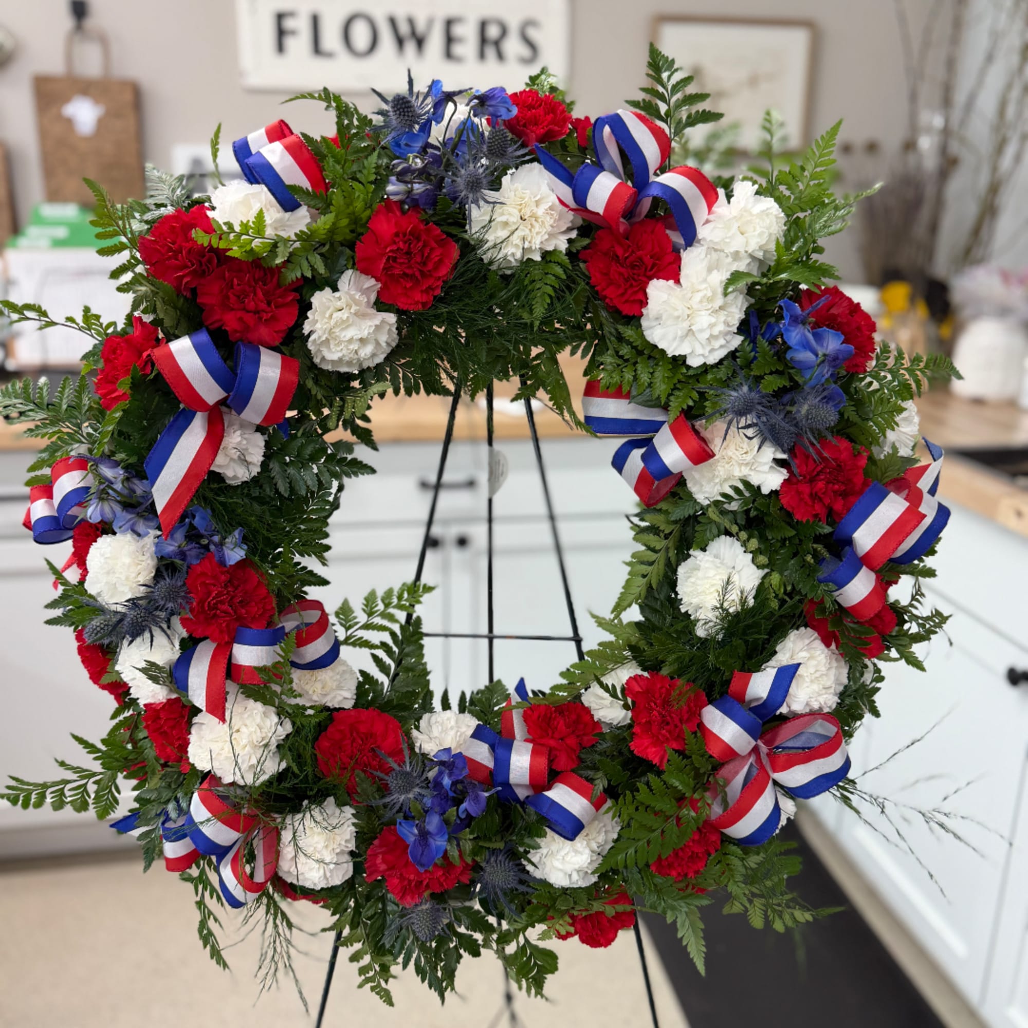 Red, white, and blue floral wreath on a stand