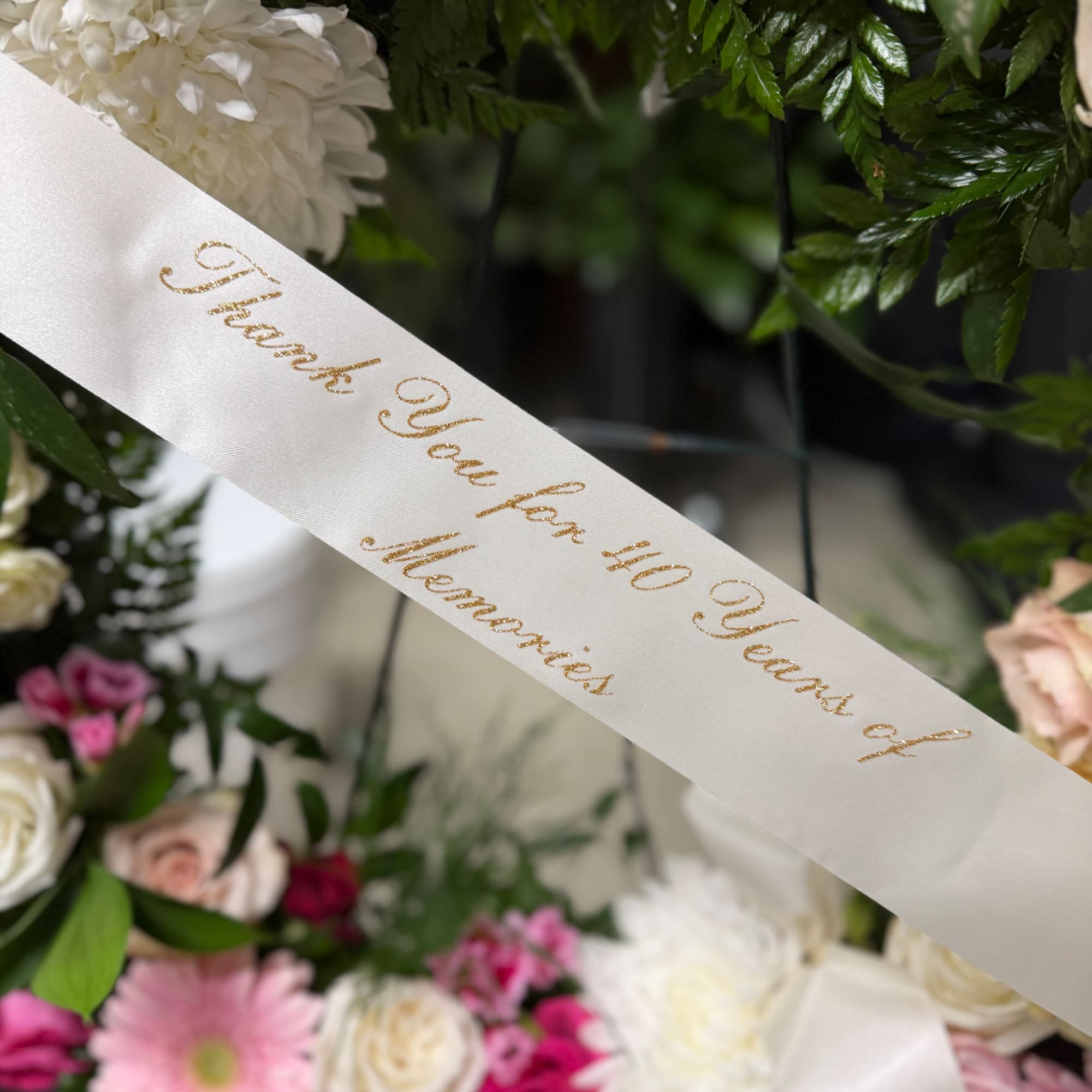 Floral arrangement with a white memorial ribbon and pink and white flowers