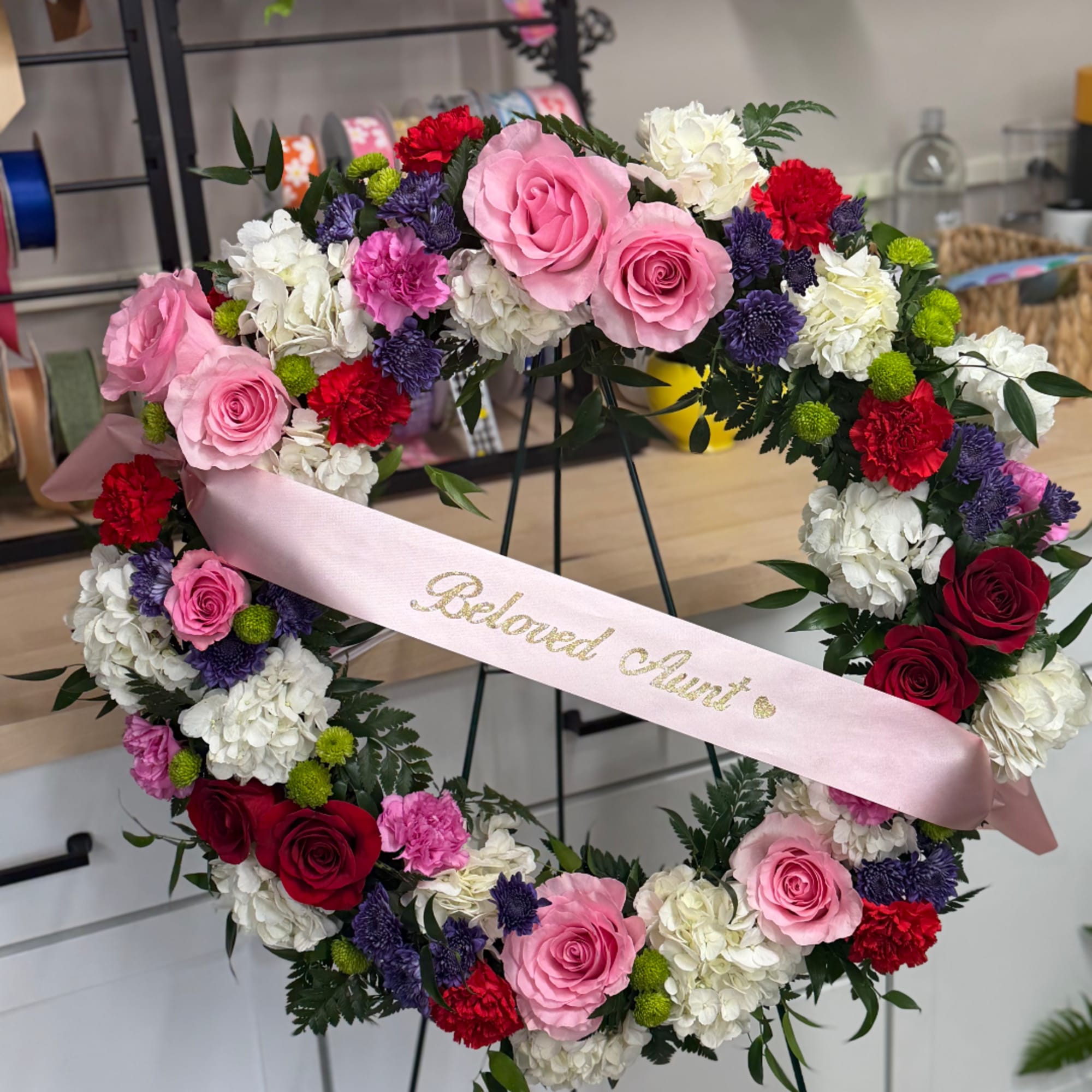 Heart-shaped floral wreath with pink and red roses and white blooms
