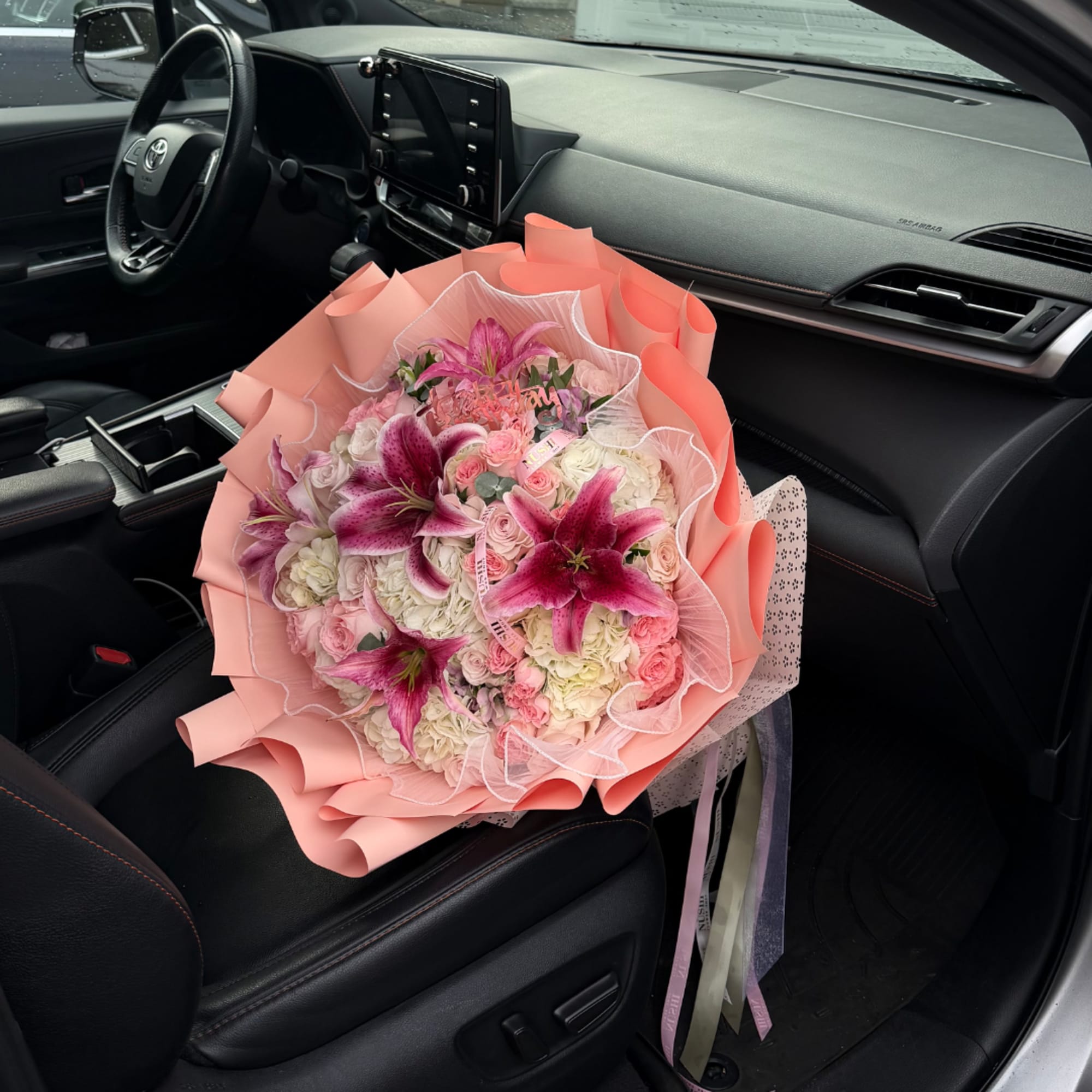 Pink and white bouquet with lilies and roses on a car seat