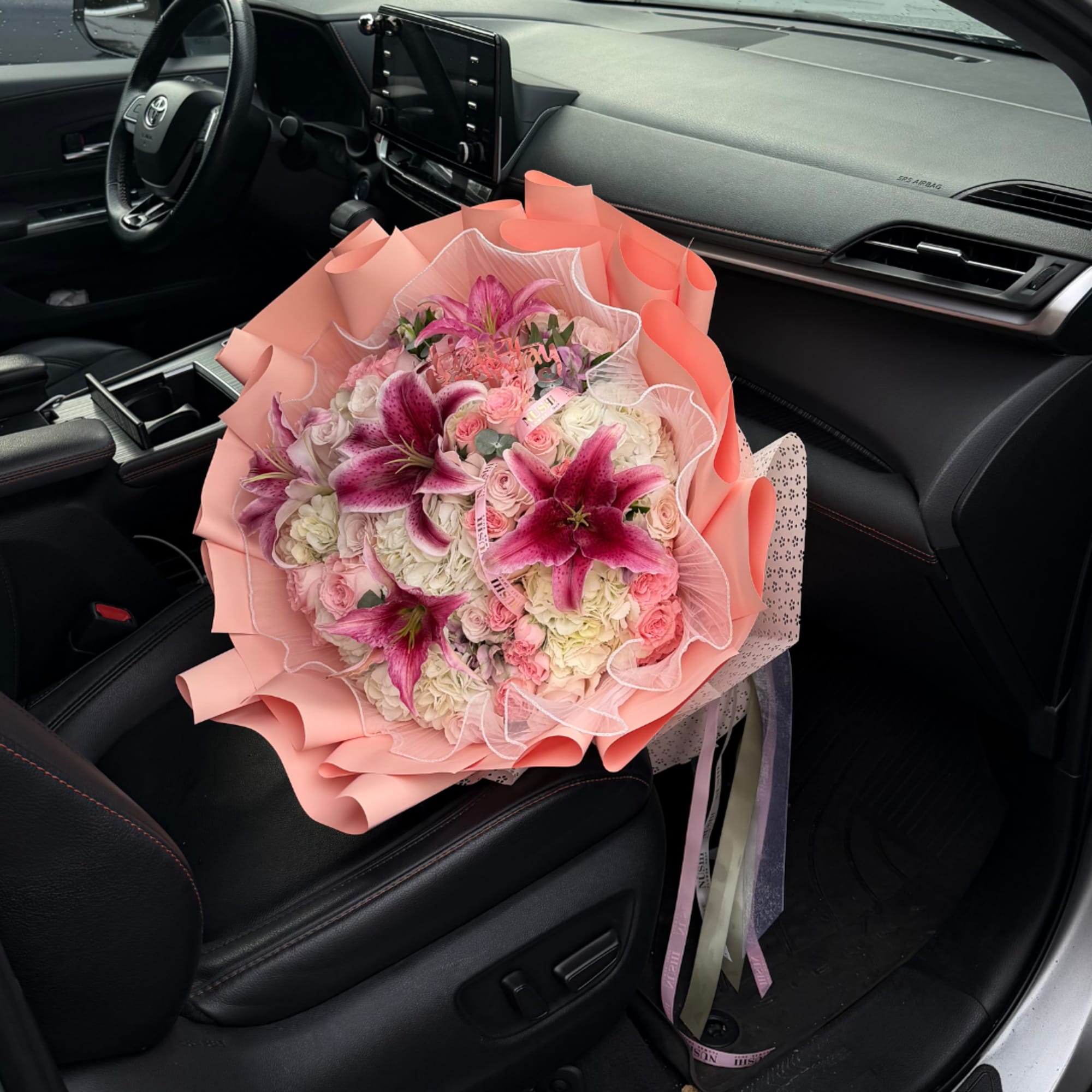 Pink and white bouquet with lilies and roses wrapped in peach paper