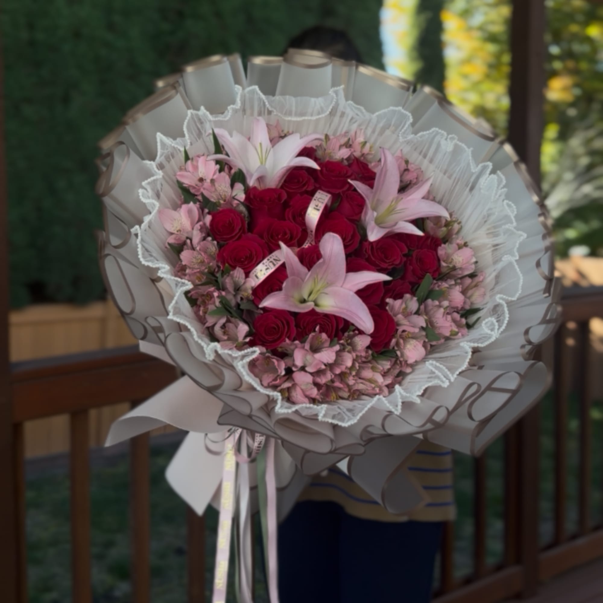 Bouquet of red roses and pink lilies wrapped in white paper