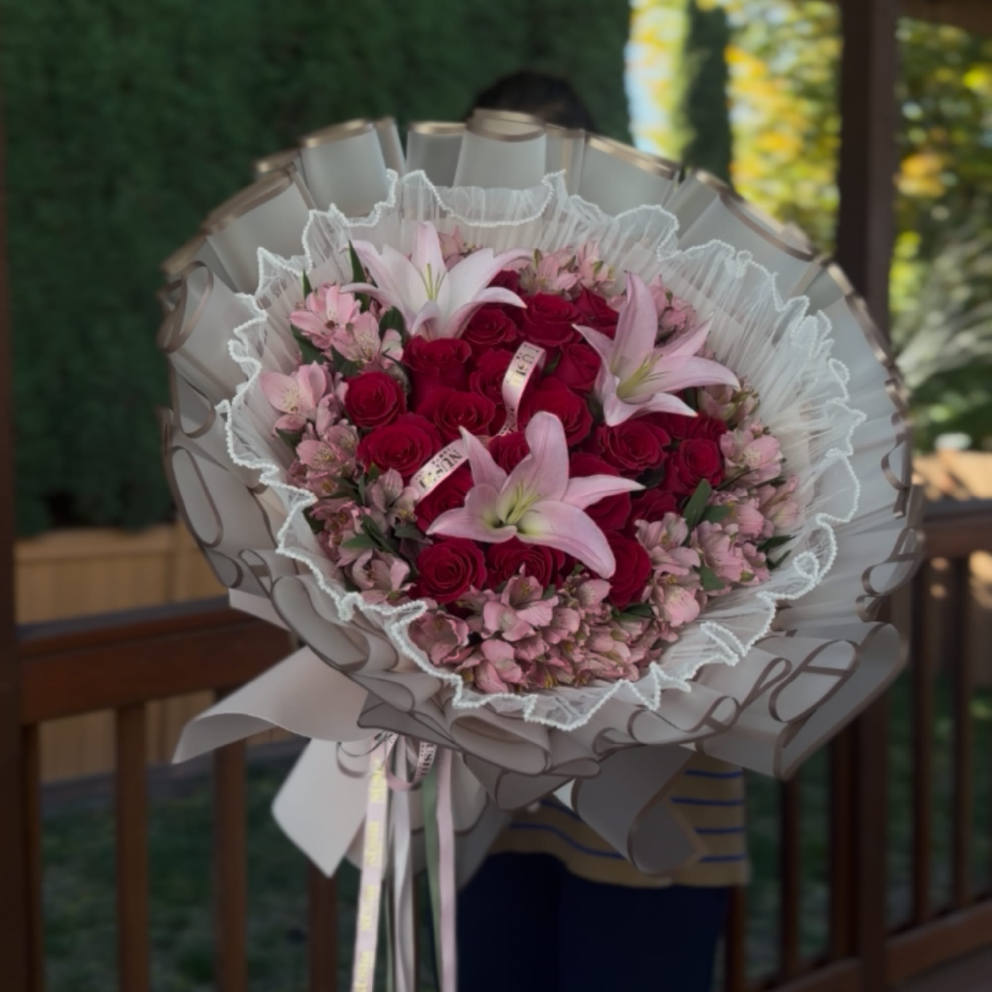Bouquet of red roses and pink lilies wrapped in white paper