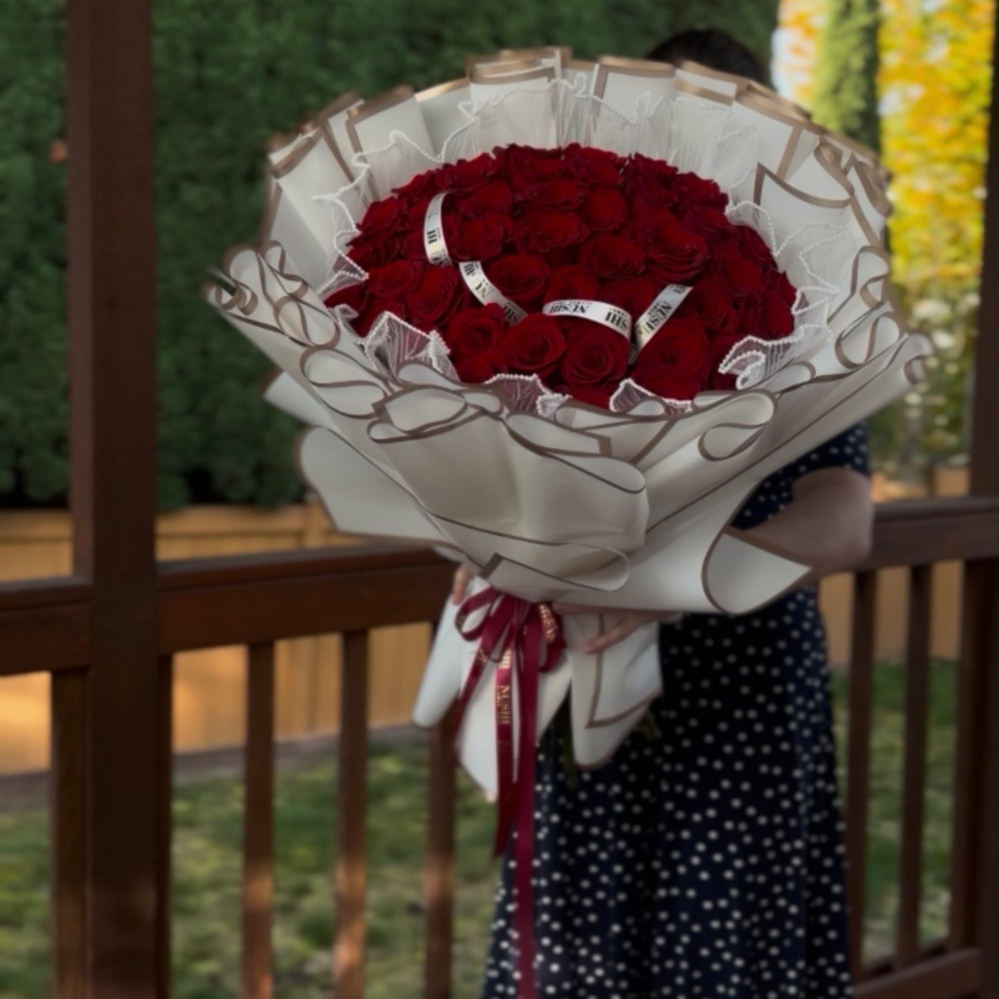 Large bouquet of red roses wrapped in cream paper with a ribbon