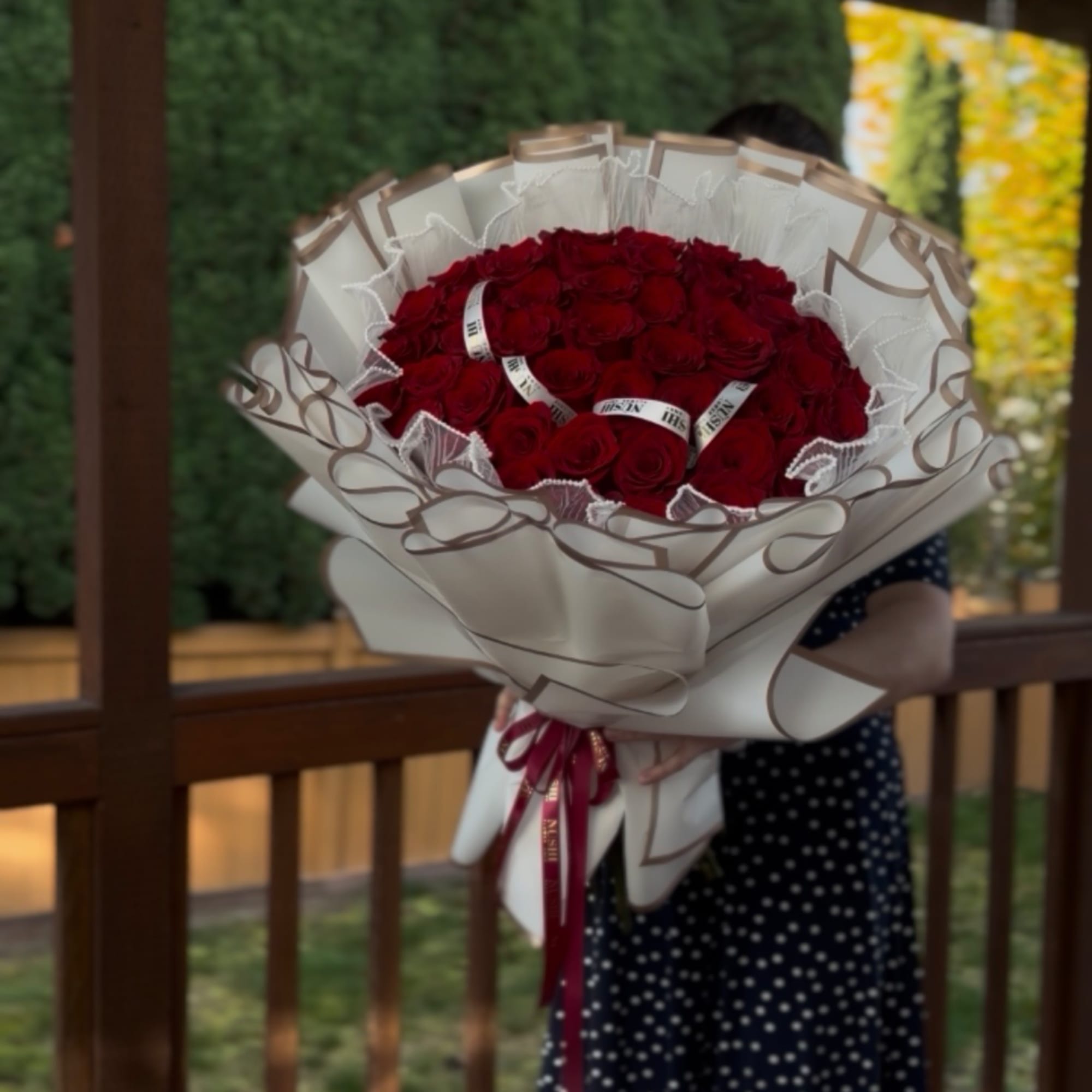 Large bouquet of red roses wrapped in cream paper with a ribbon