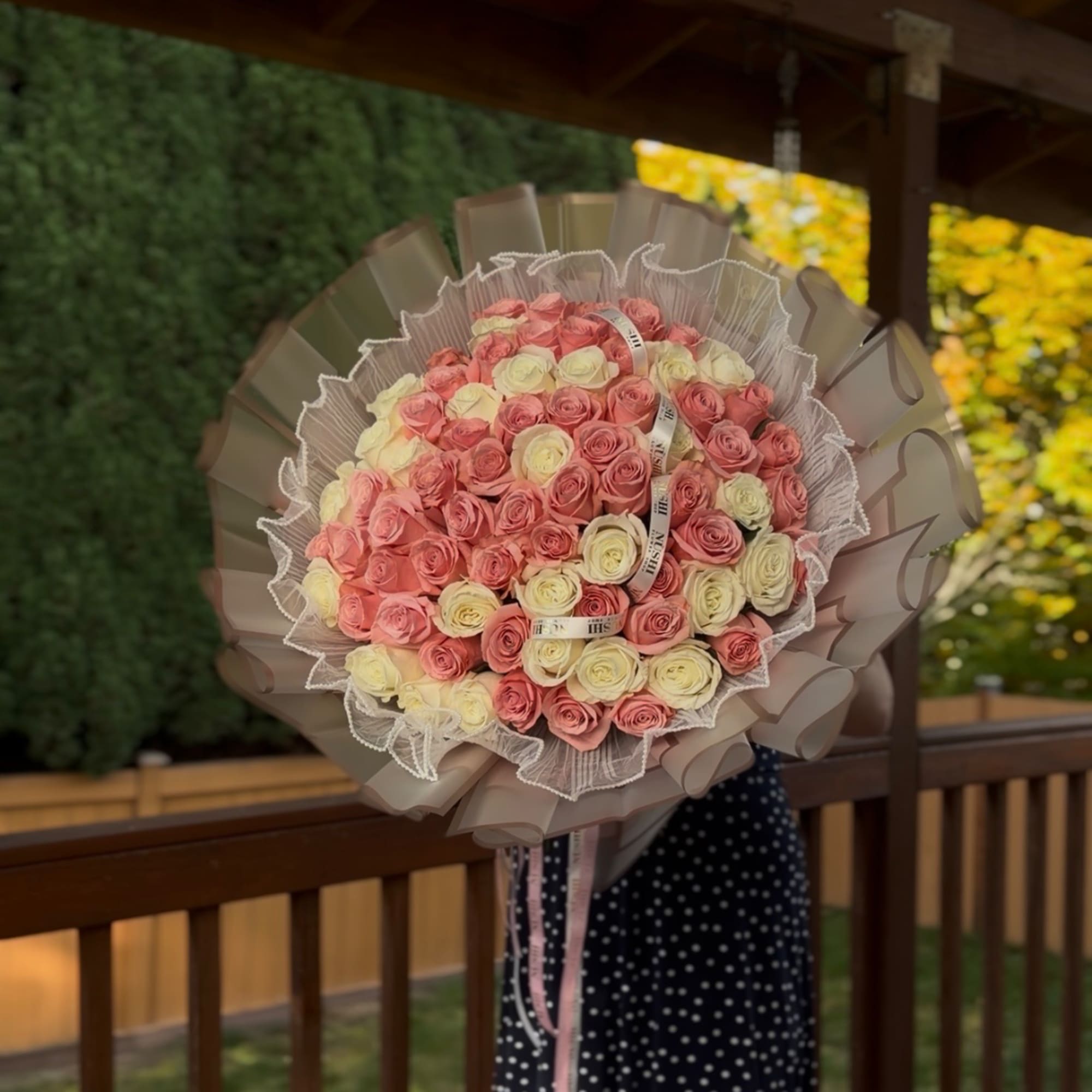 Large bouquet of pink and cream roses wrapped in decorative paper