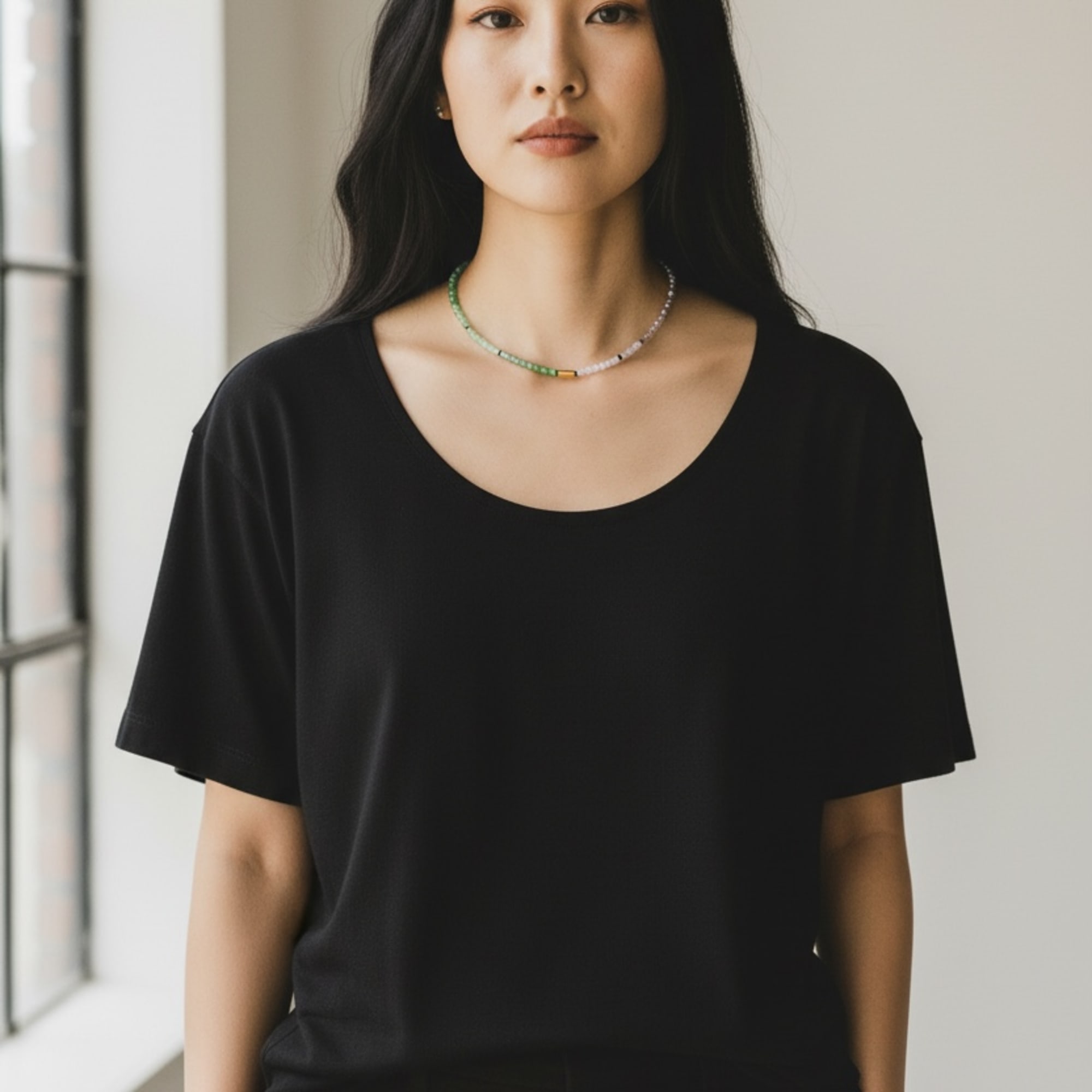 Portrait of a woman in a black top wearing a beaded necklace