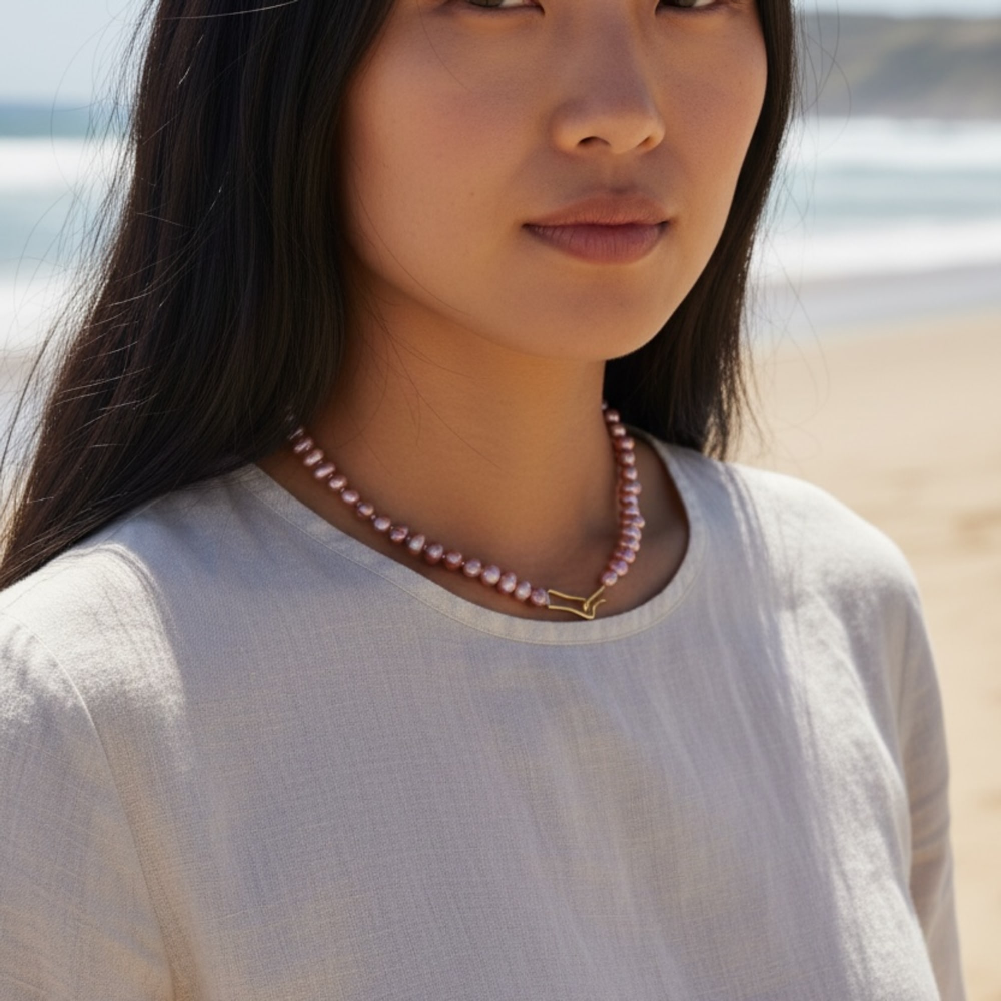 Portrait of a woman wearing a pearl necklace on a beach