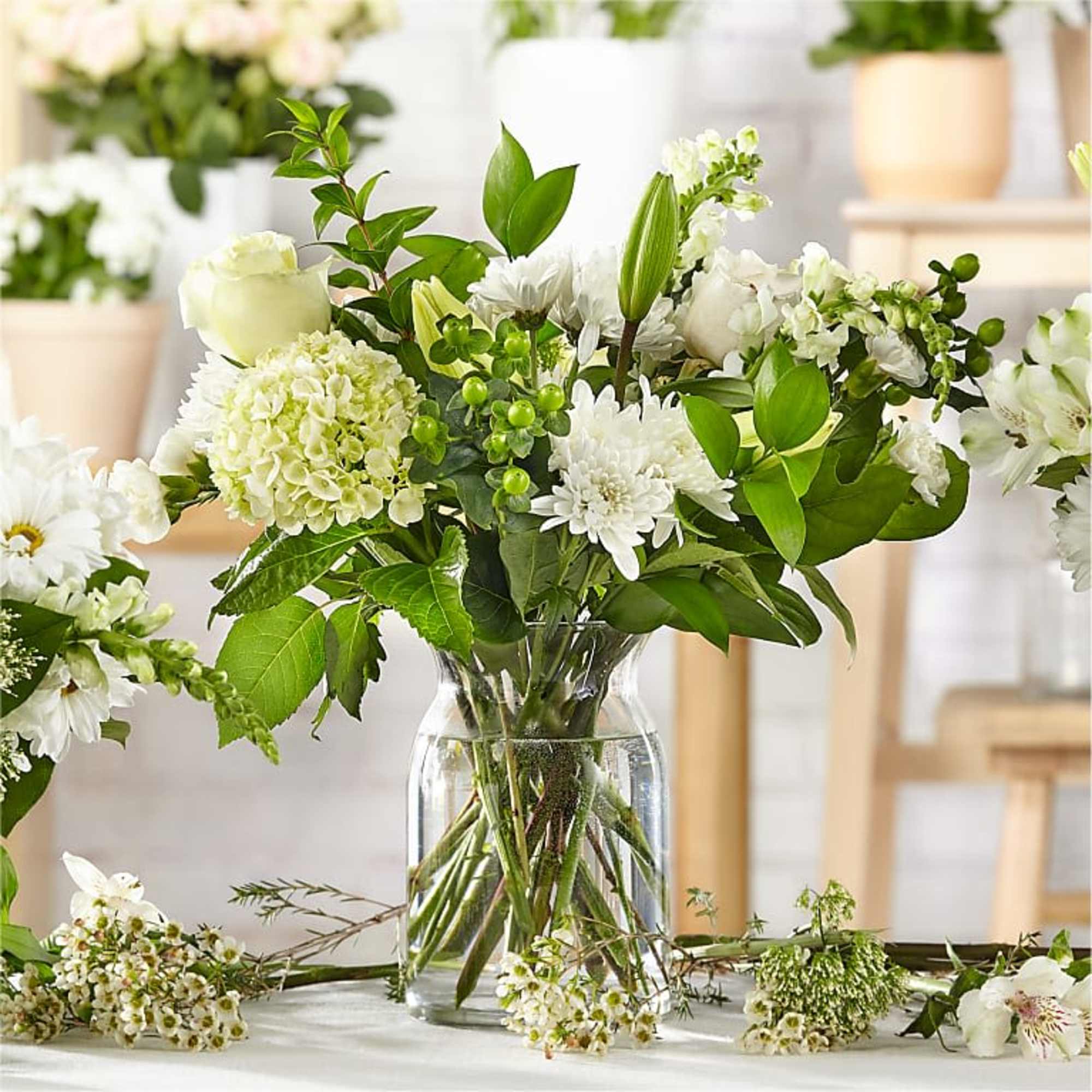 White floral bouquet in a clear glass vase with green foliage