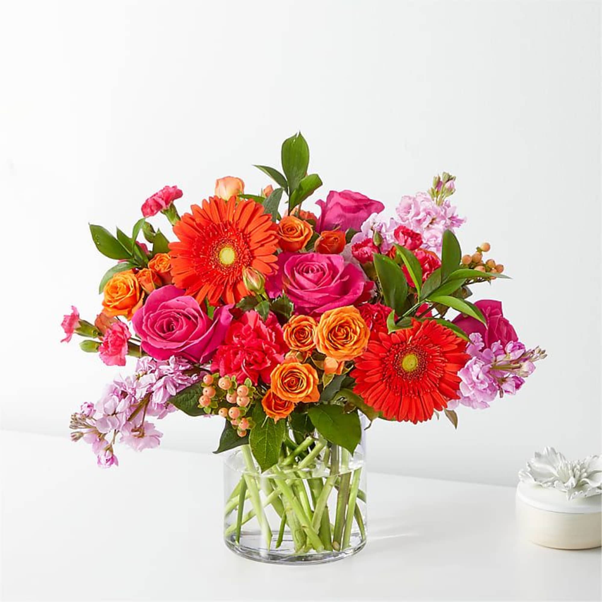 Bright mixed bouquet of roses and gerbera daisies in a clear glass vase