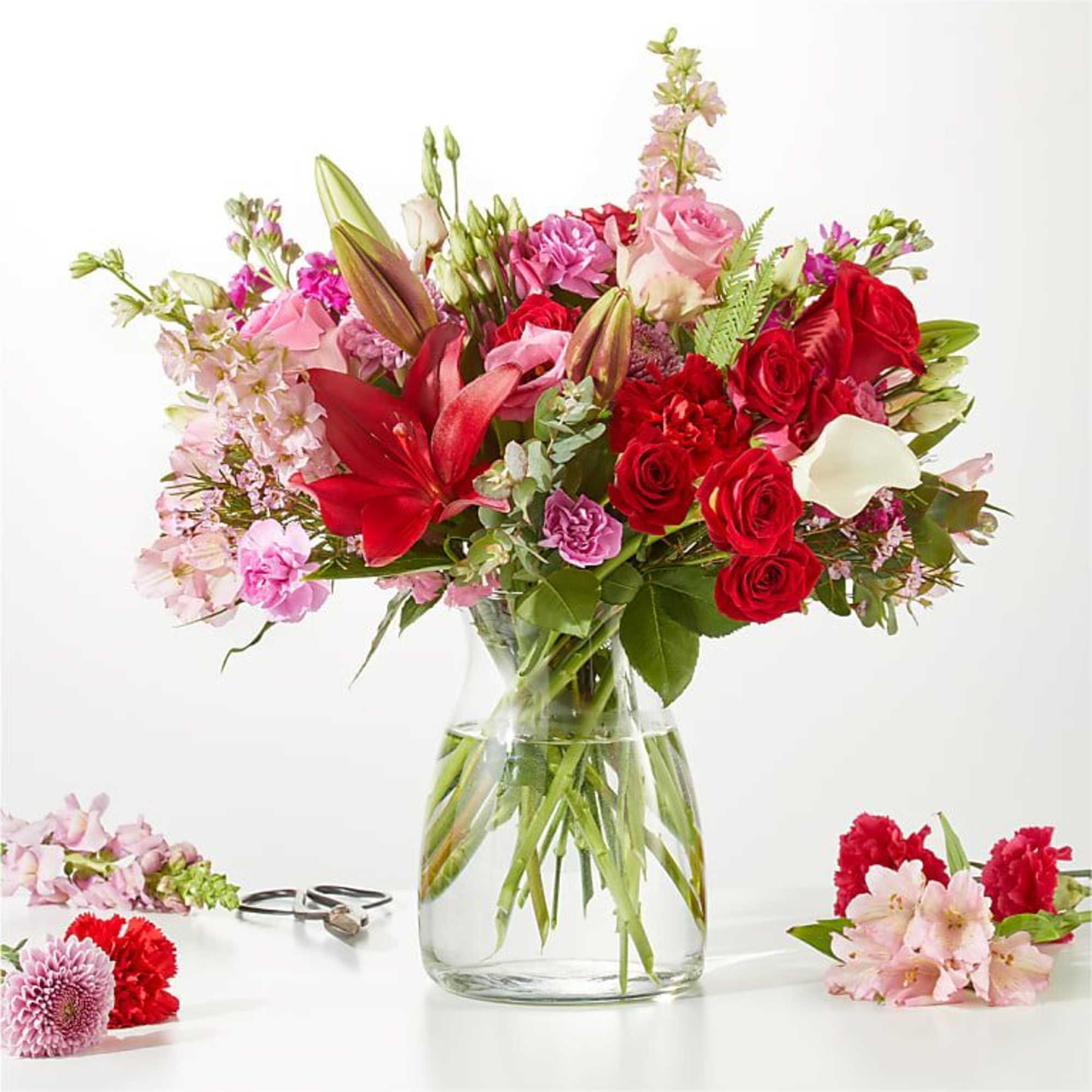 Mixed bouquet of red and pink flowers in a clear glass vase