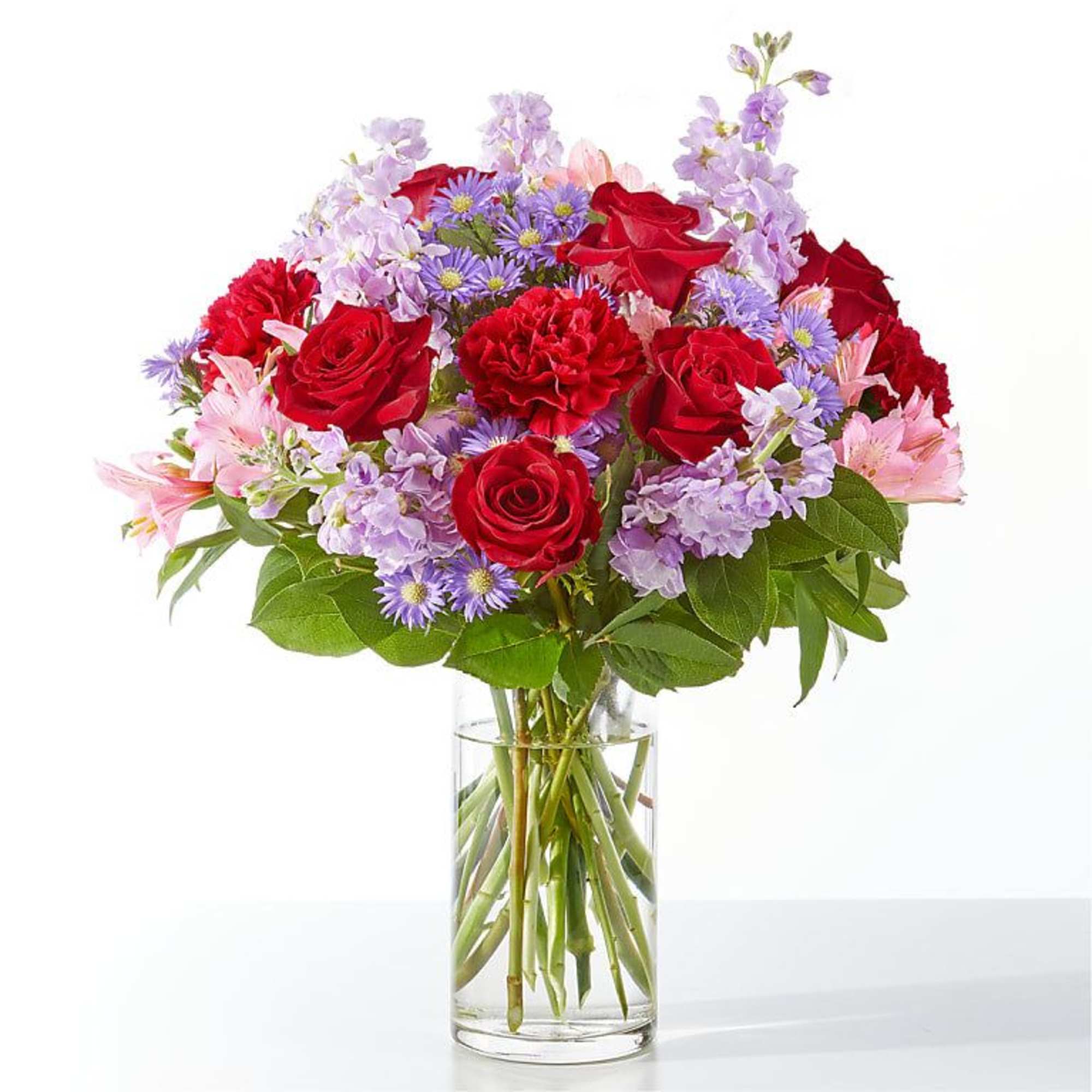 Bouquet of red roses, purple flowers, and pink blooms in a clear glass vase