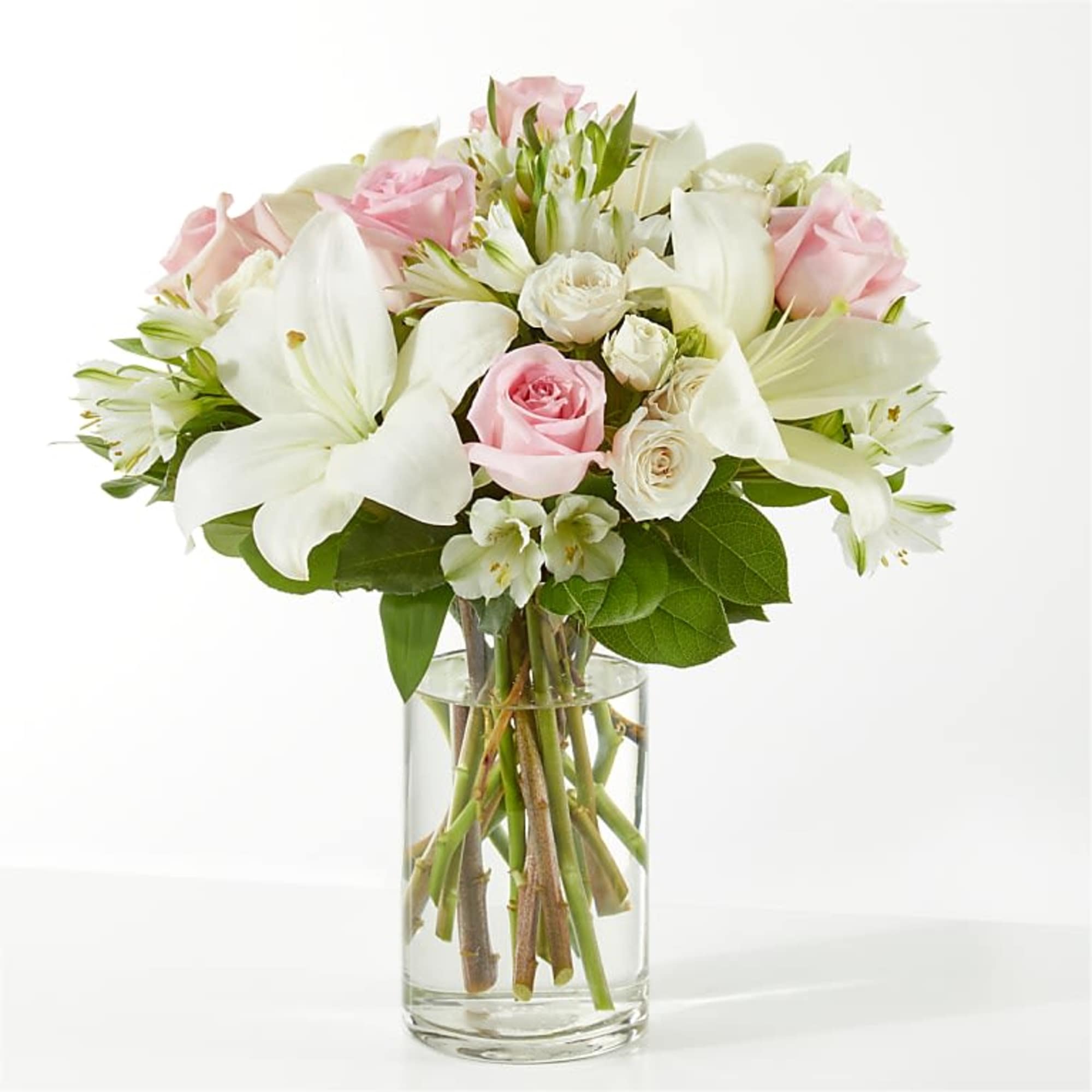 Pink and white bouquet of roses and lilies in a clear glass vase