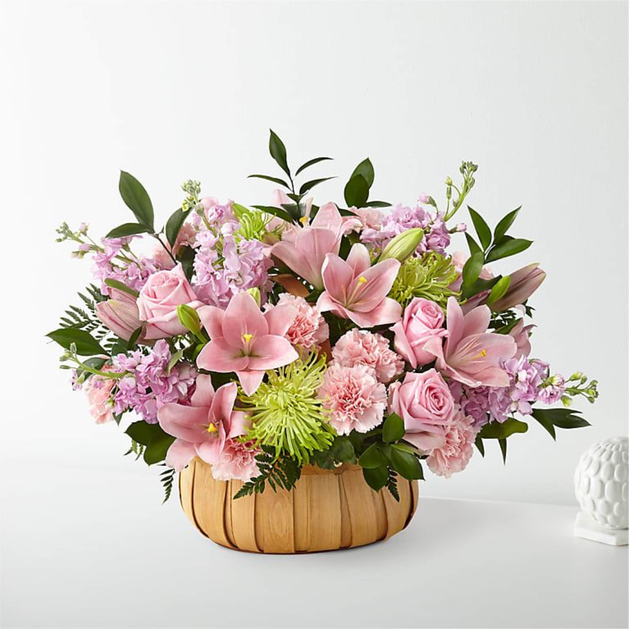 Pink lilies and roses in a woven basket arrangement