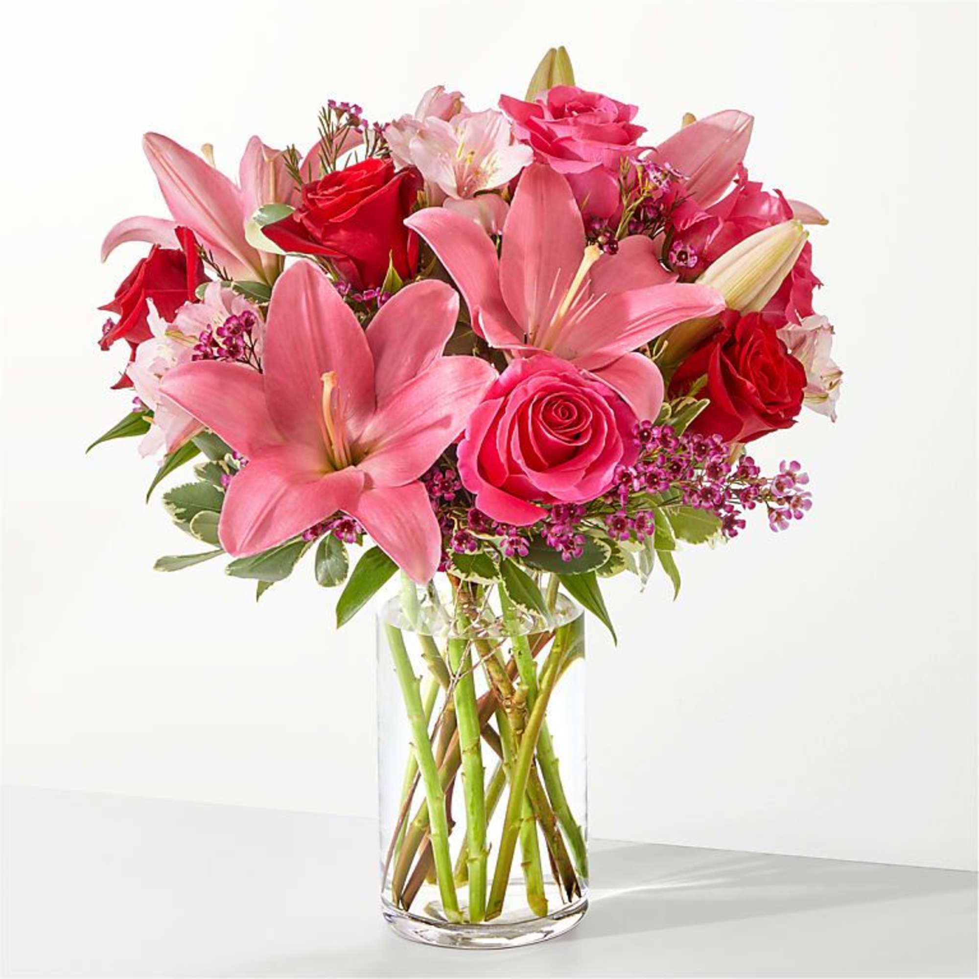 Pink lilies and red roses in a clear glass vase