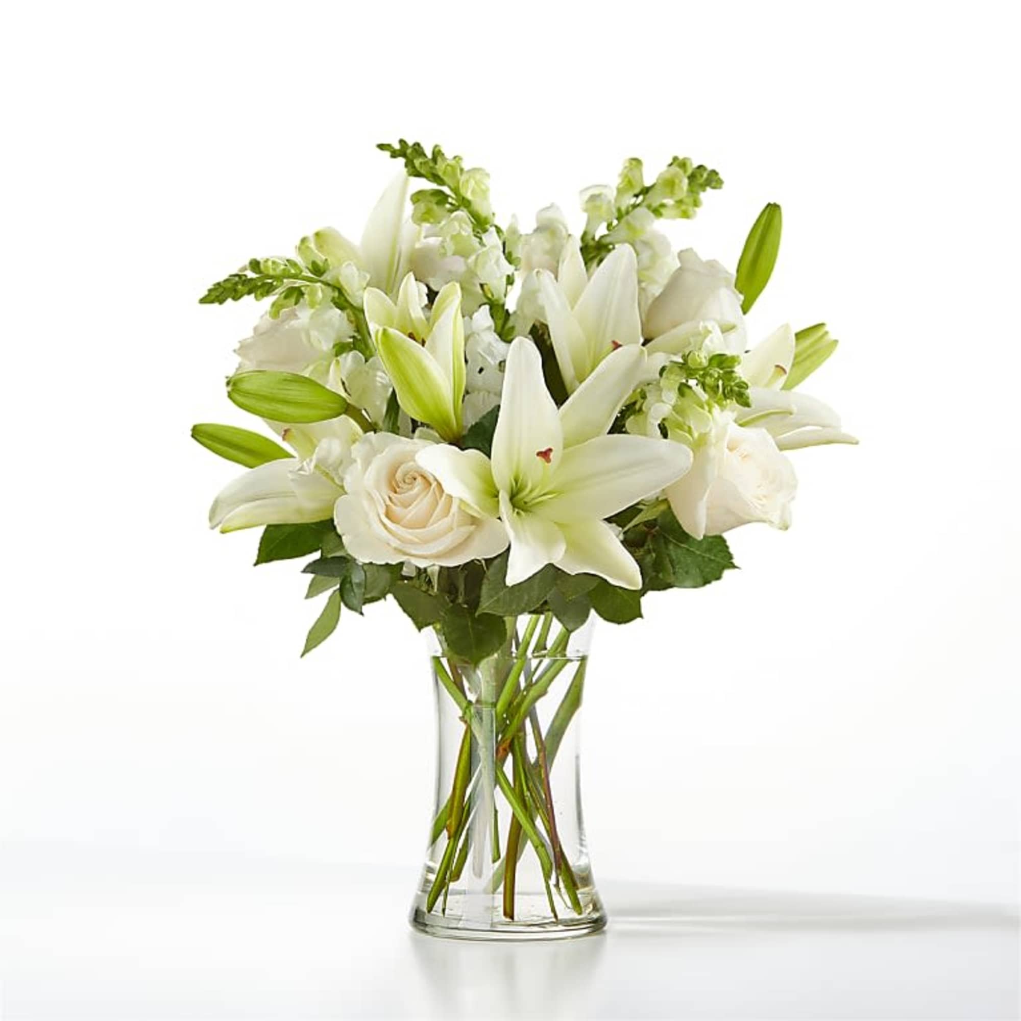 White lilies and roses arranged in a clear glass vase