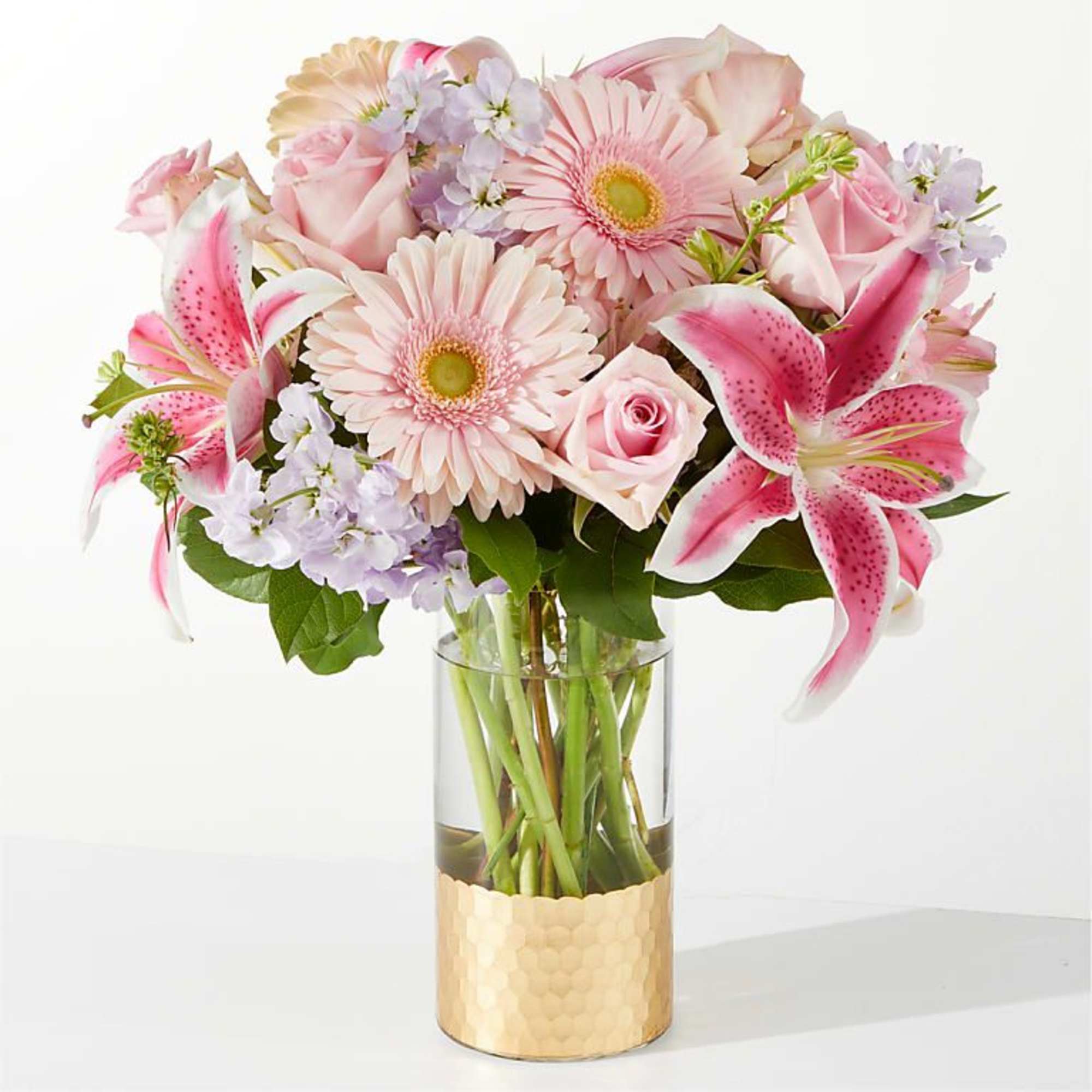 Pink lilies, roses, and daisies arranged in a glass vase