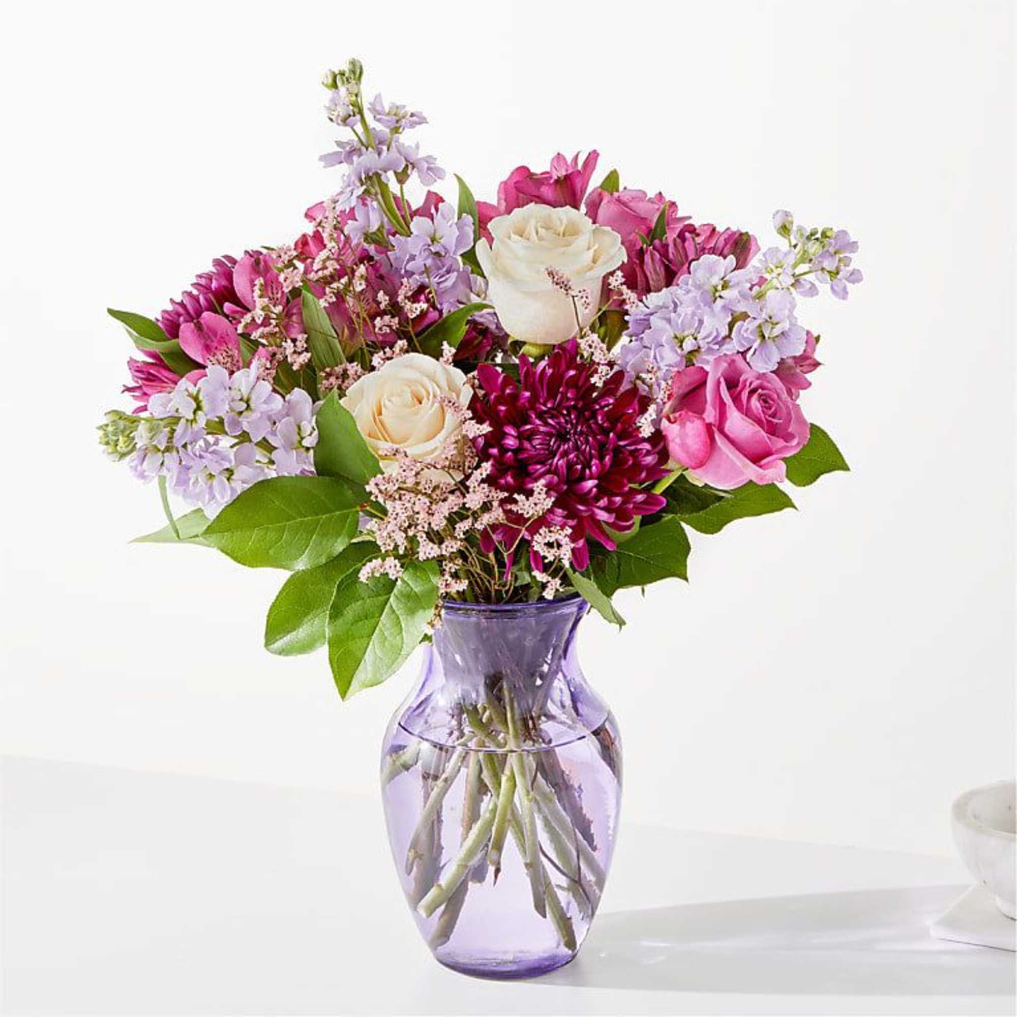 Pink and lavender mixed bouquet in a purple glass vase