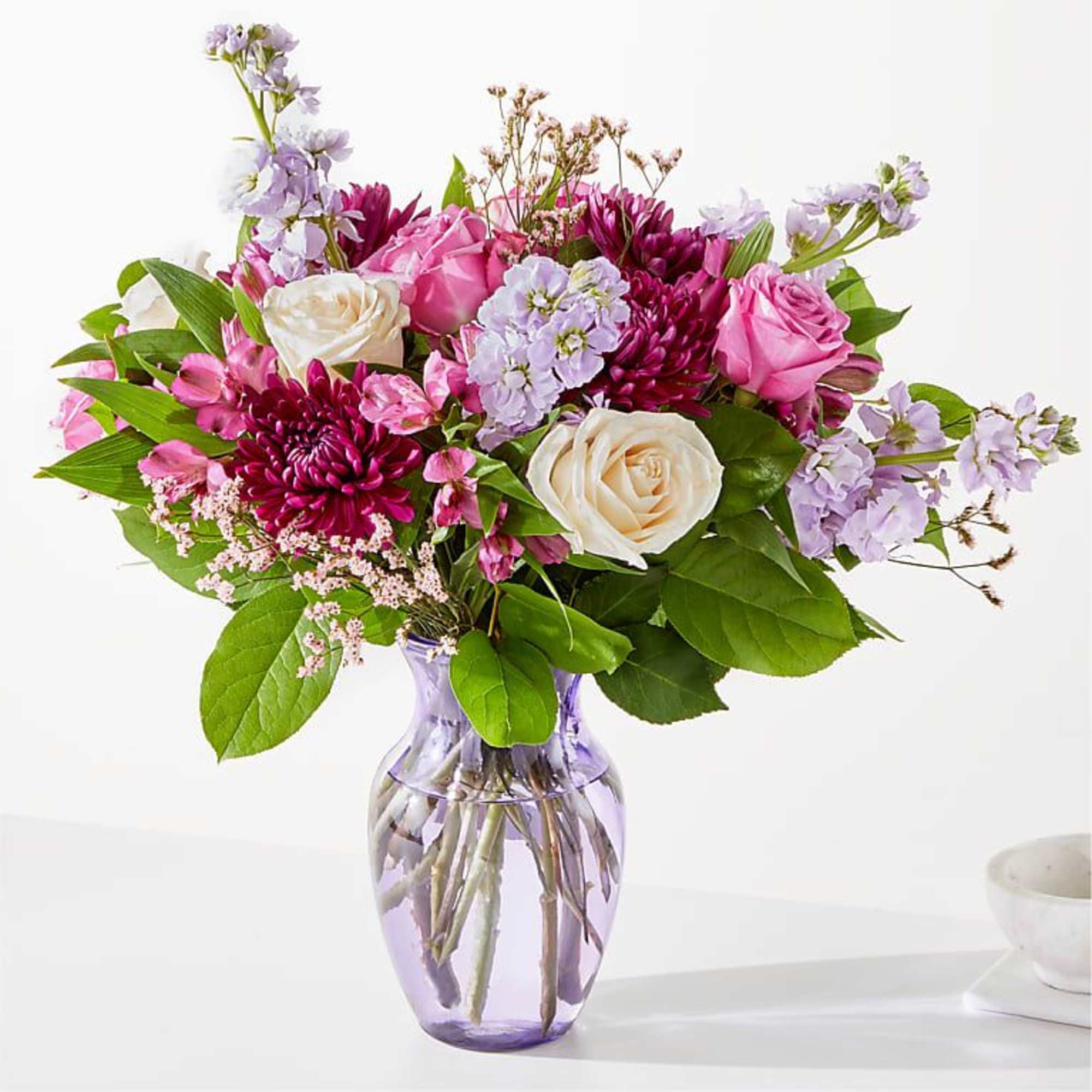 Pink and white roses with purple flowers in a glass vase