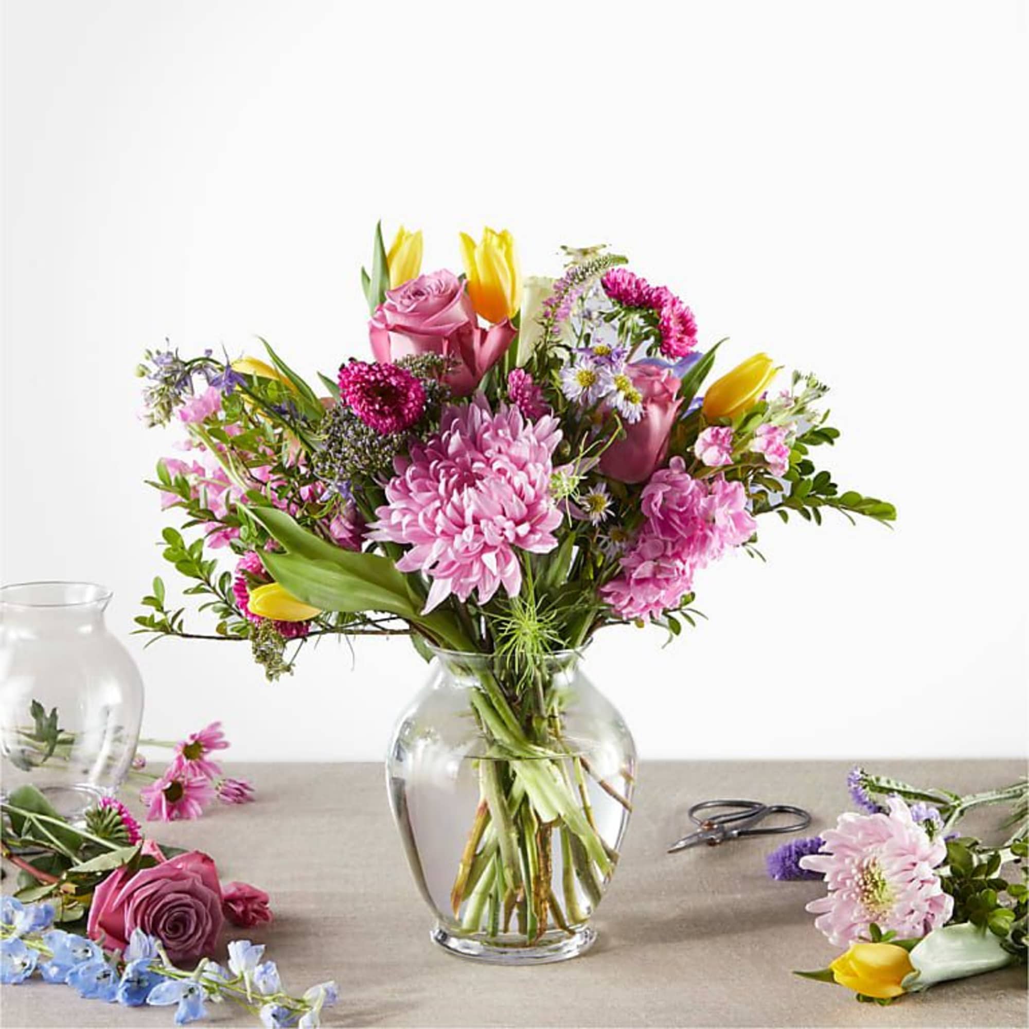 Mixed pink and yellow flowers arranged in a clear glass vase