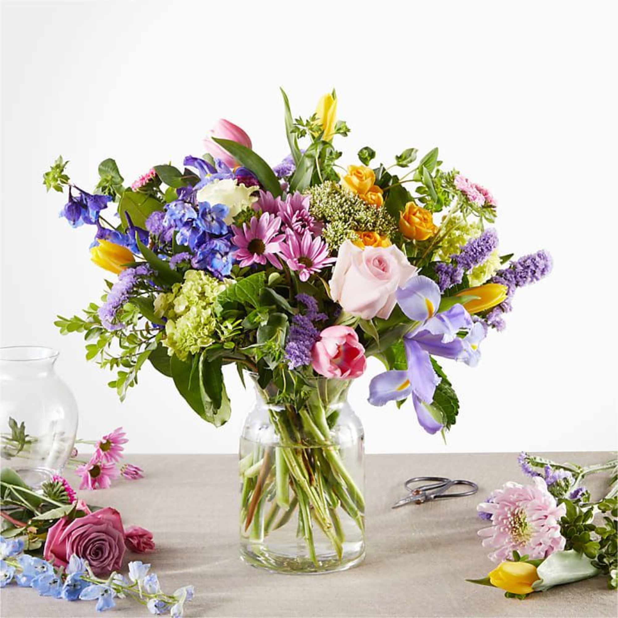 Mixed bouquet in a clear glass vase with pink, purple, yellow, and white flowers