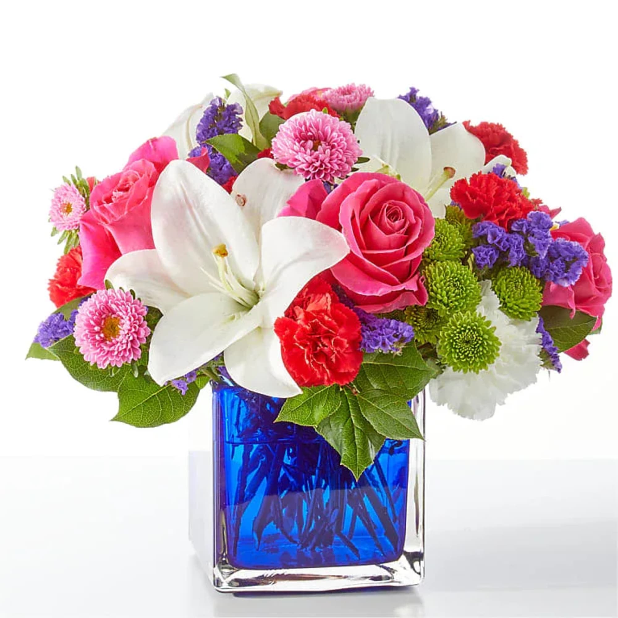 Mixed bouquet of pink roses, white lilies, and colorful mums in a blue glass vase