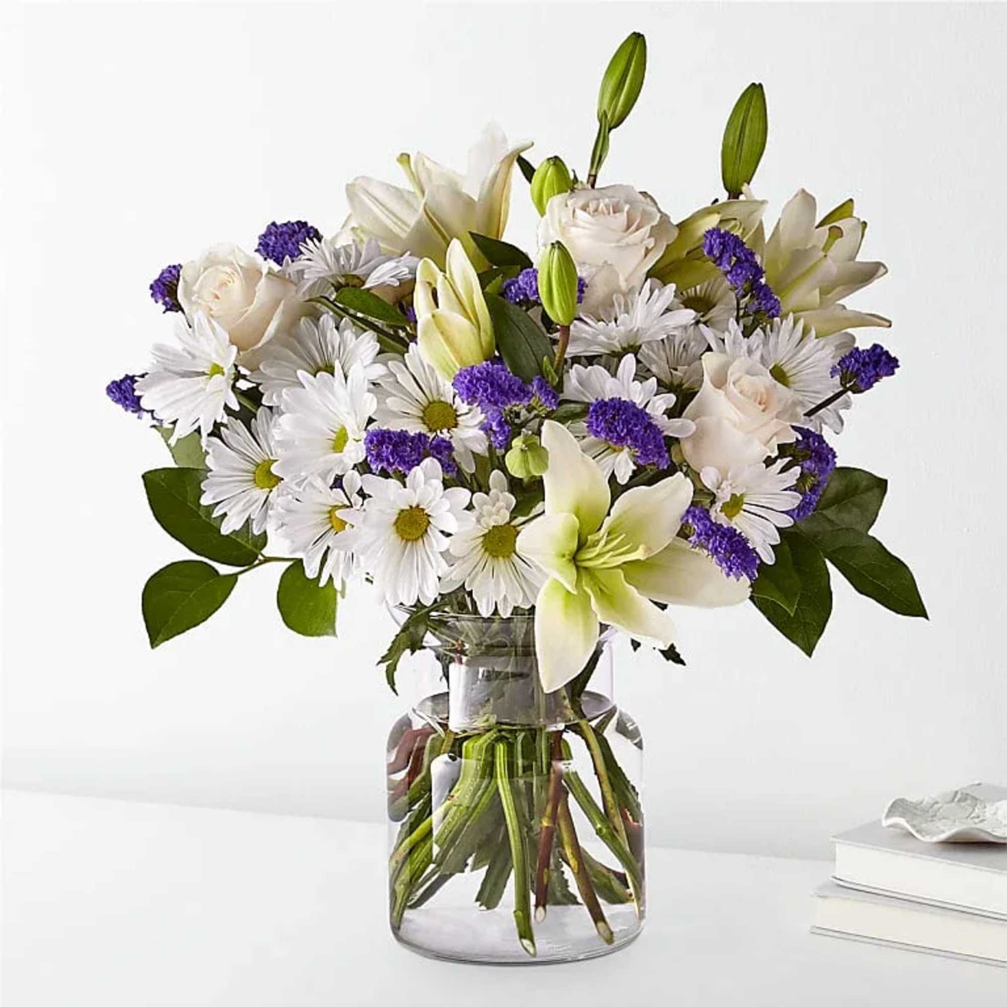 Bouquet of white lilies, roses, and daisies in a glass vase