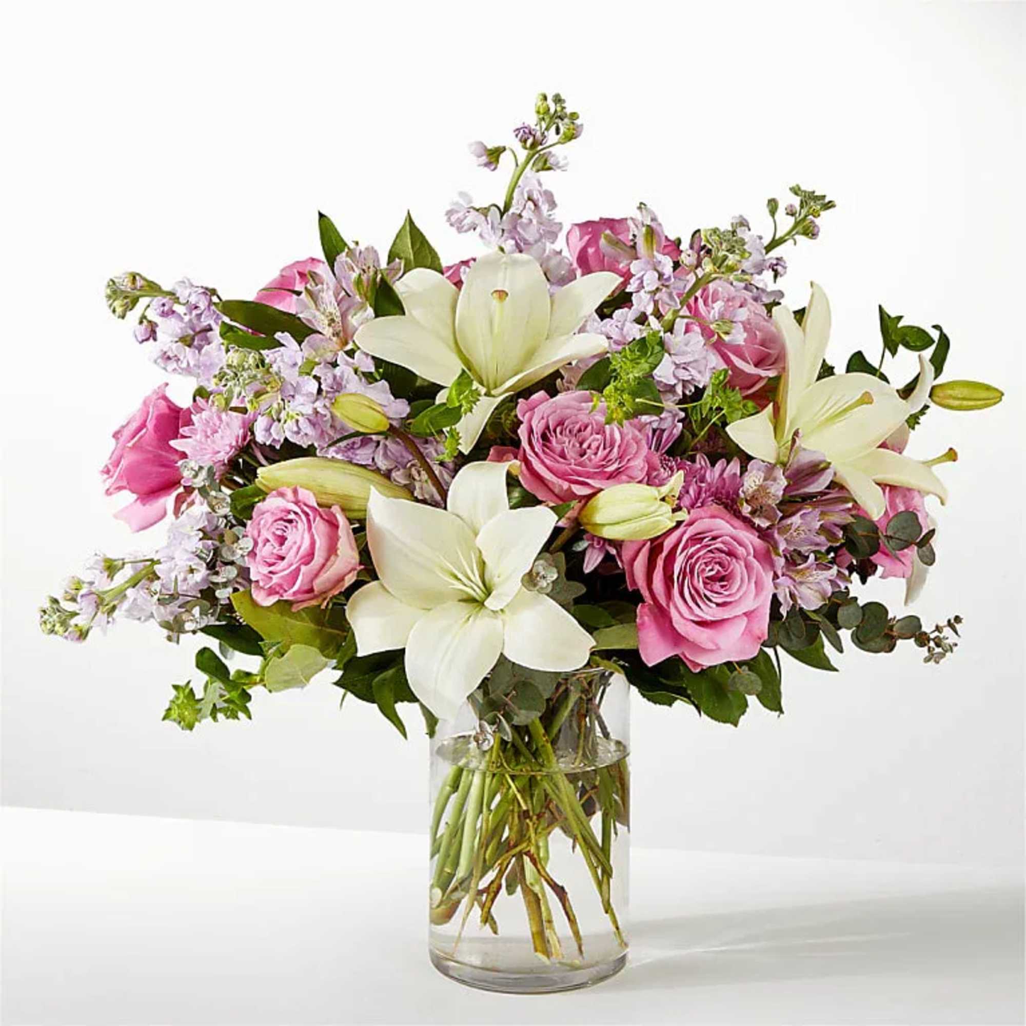 Pink roses and white lilies arranged in a clear glass vase