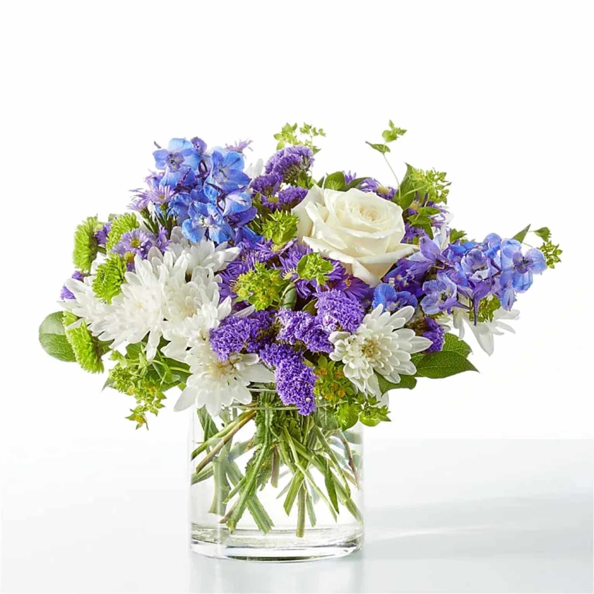 Blue, purple, and white flowers arranged in a clear glass vase