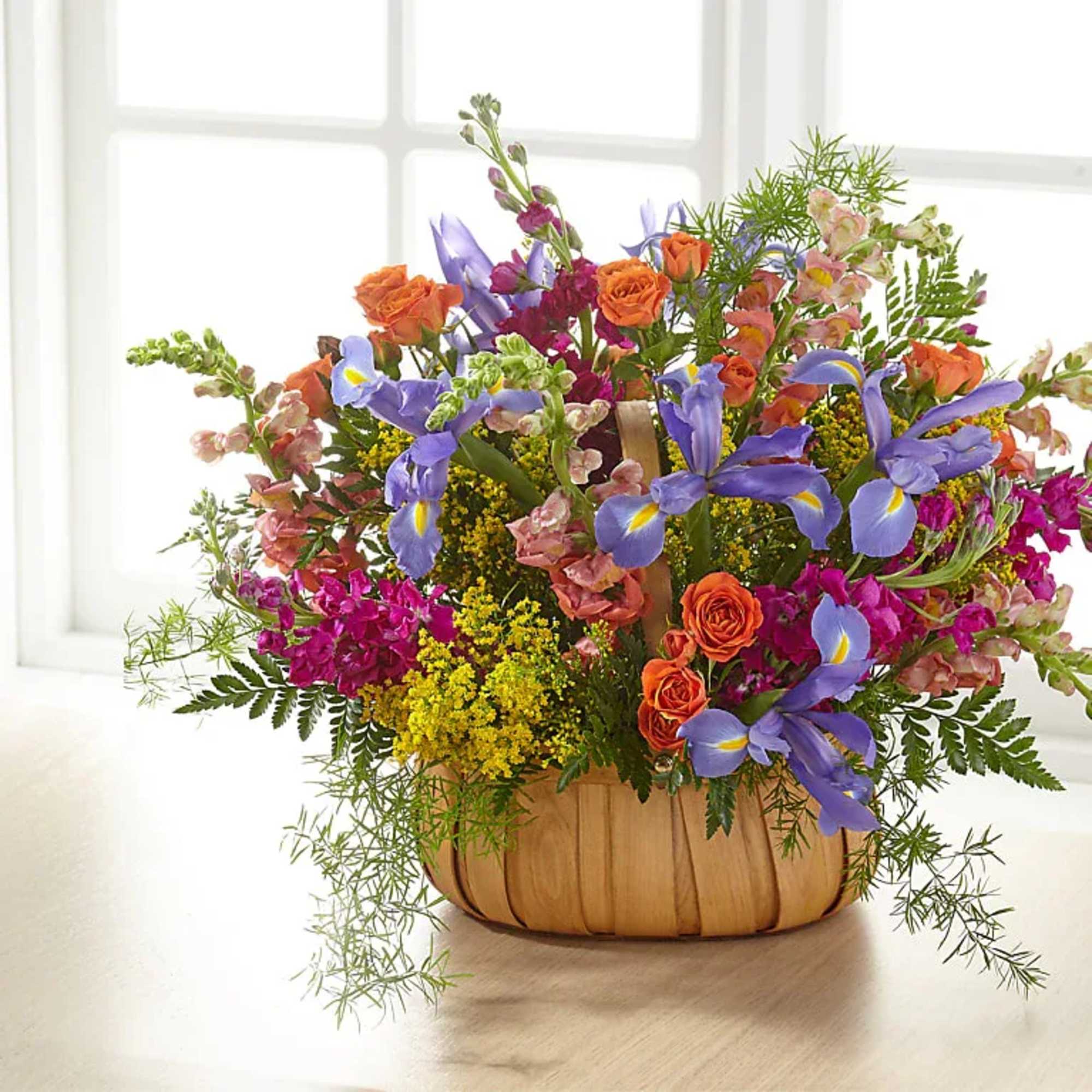 Mixed bouquet of orange roses and purple irises in a wooden basket